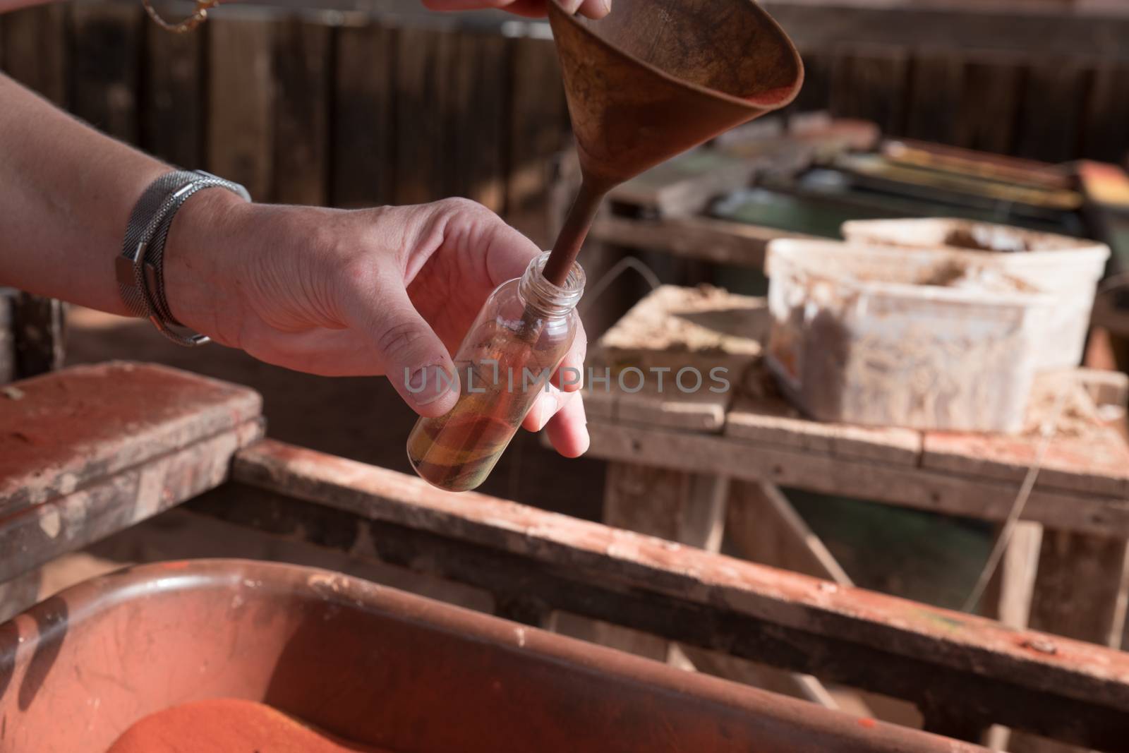 Close up of woman hands filling souvenir bottle with colorful sand. Handmade souvenir is feature of Timna Park