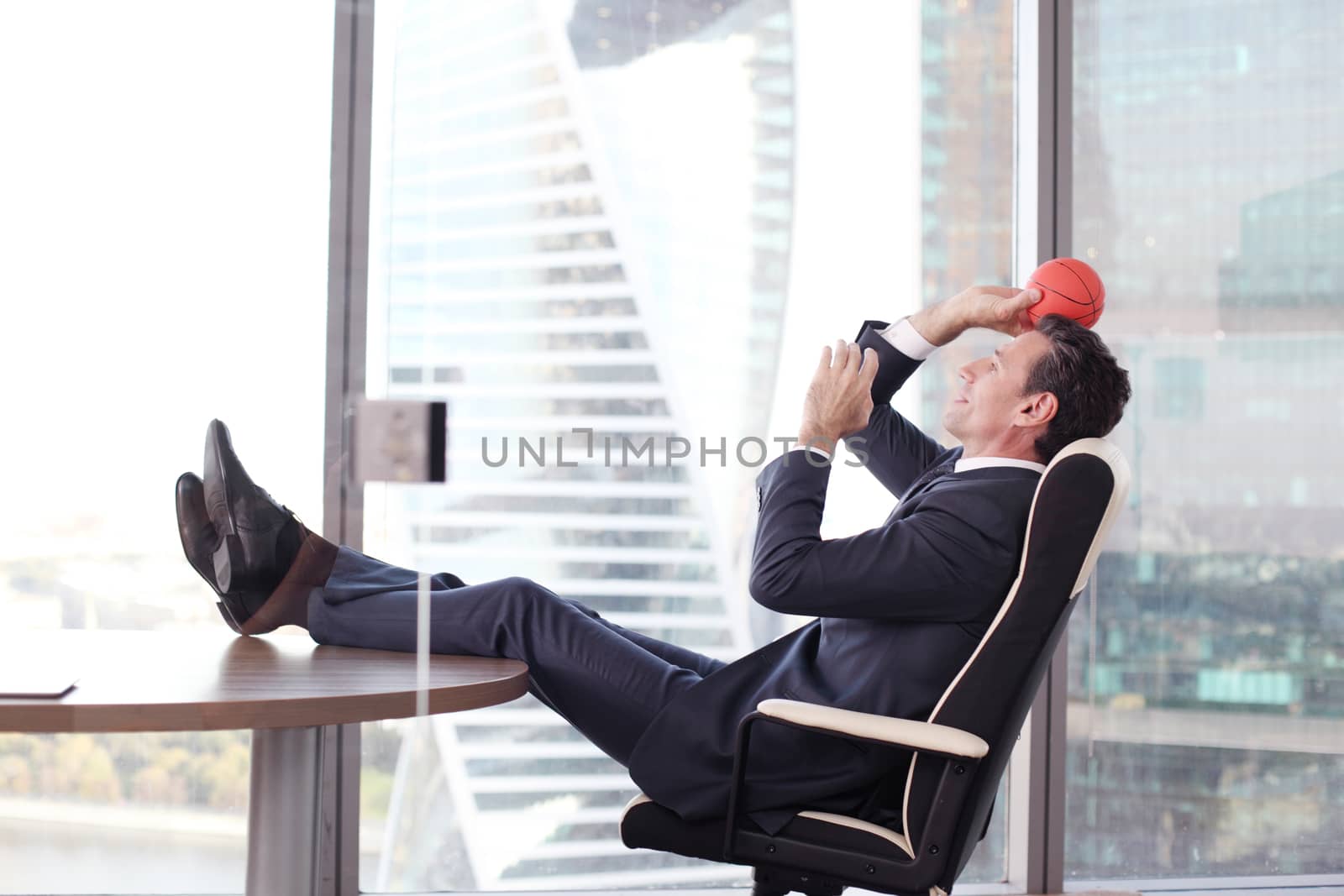 Business man playing with a basketball at the office