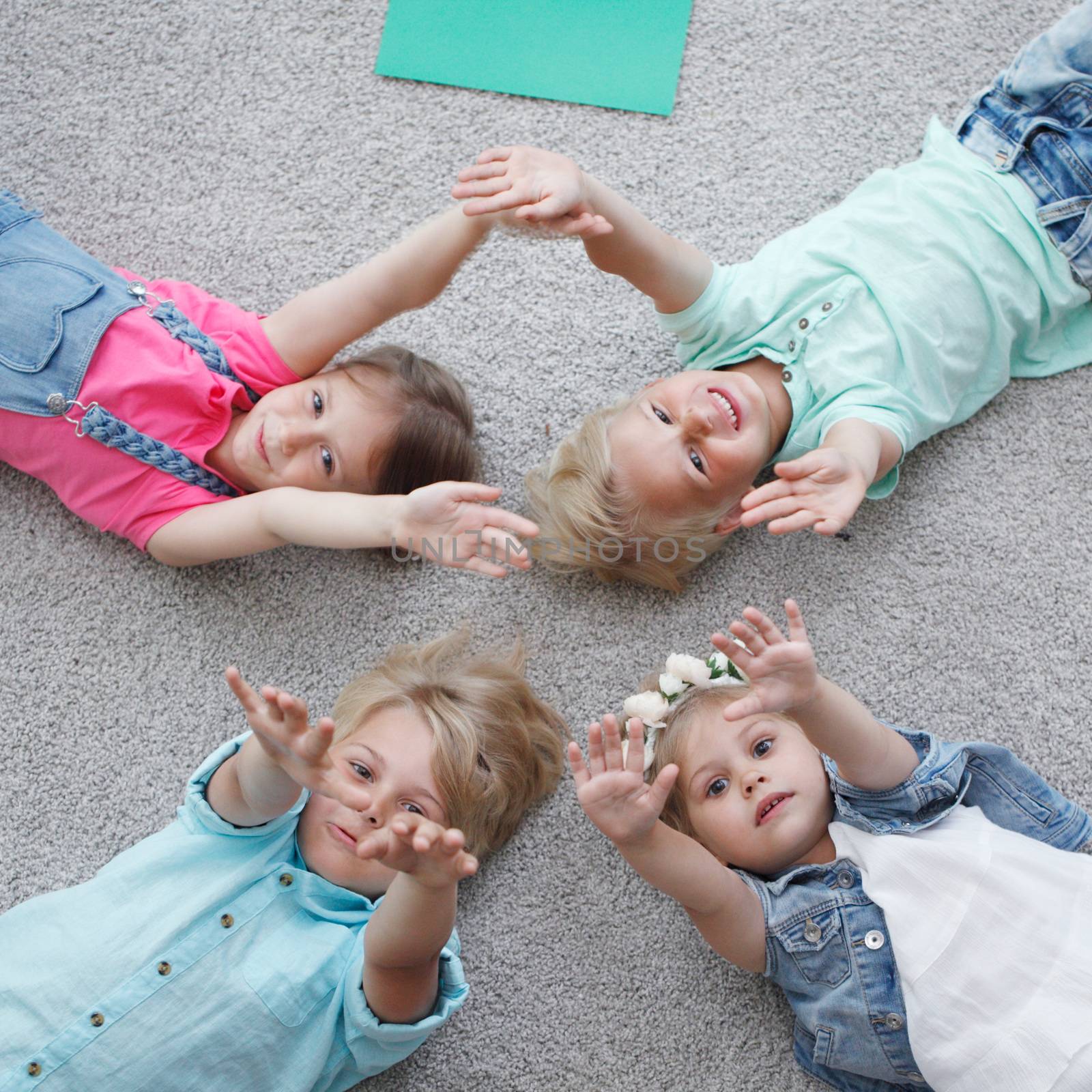 Group of happy kids laying on floor, top view