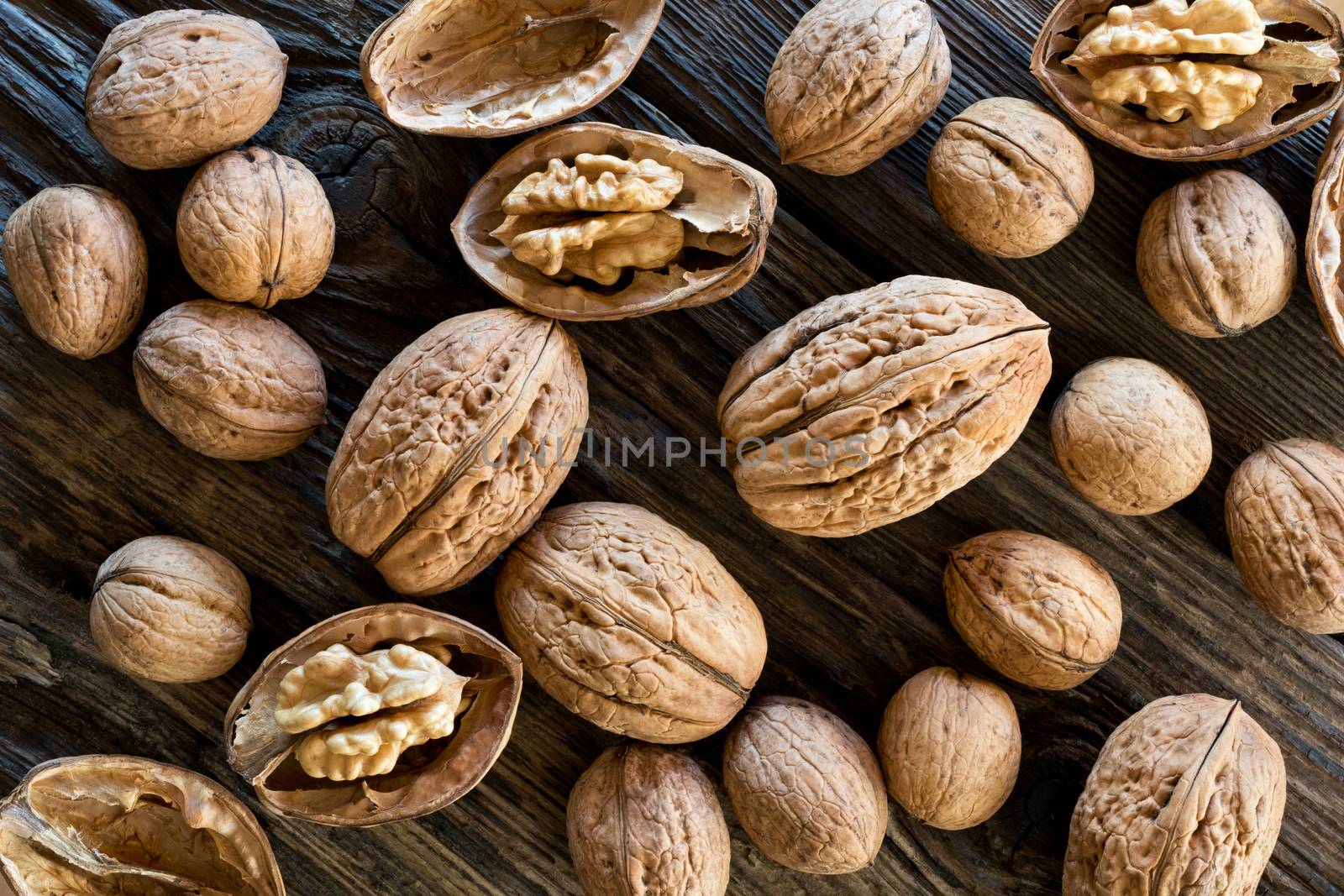 Top view of whole (unshelled) and broken walnuts on old wood