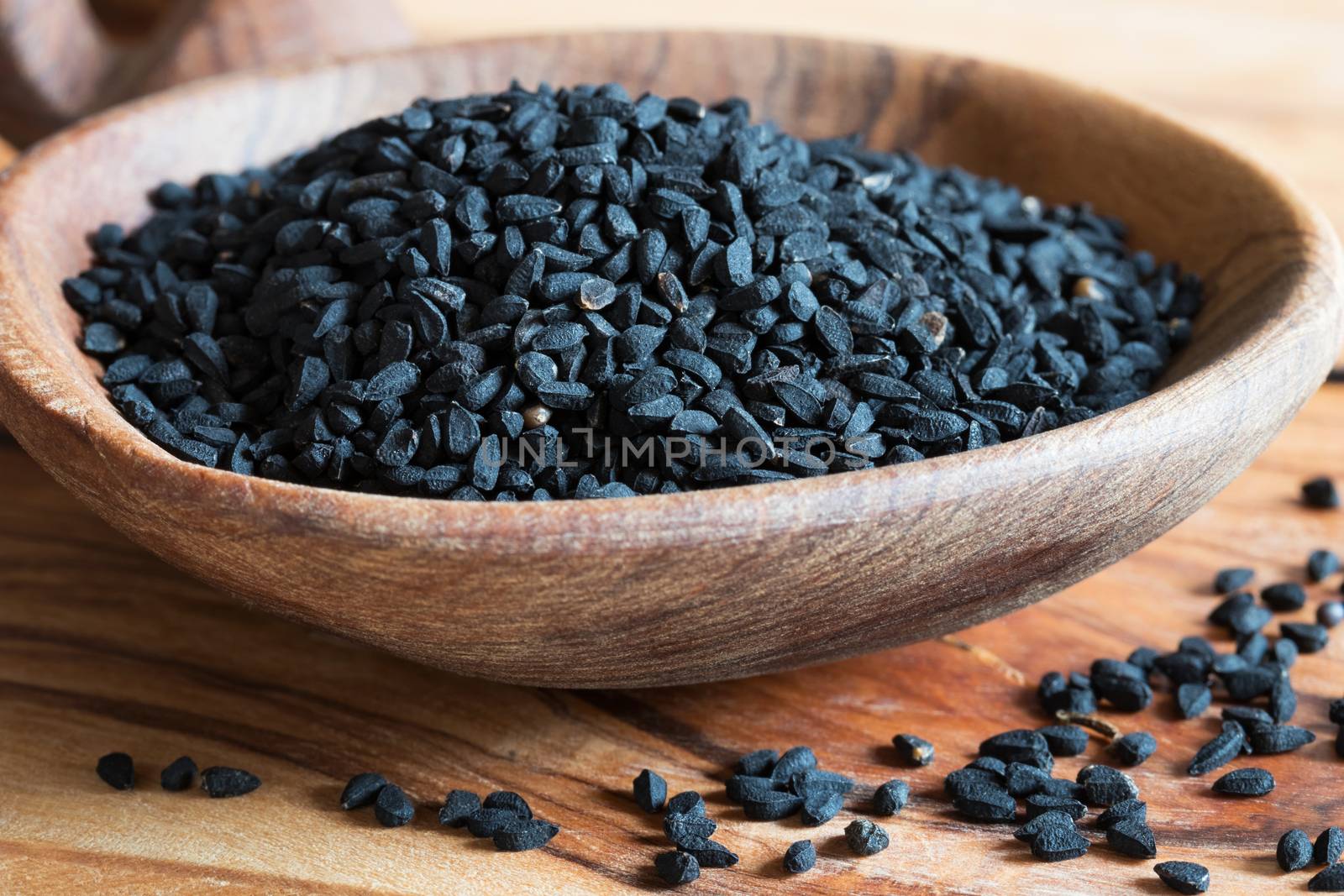 Closeup of black cumin seeds on a wooden spoon
