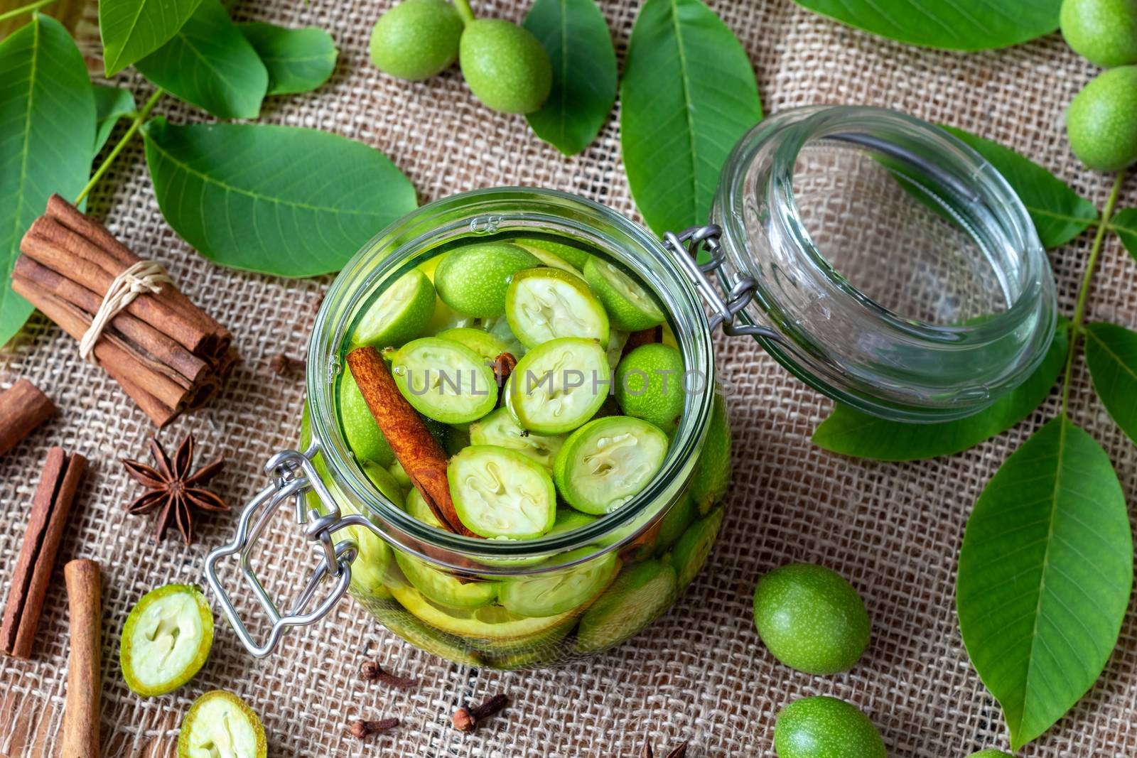 Macerating unripe walnuts, lemon and spices in alcohol in a jar, to prepare homemade tincture or liqueur