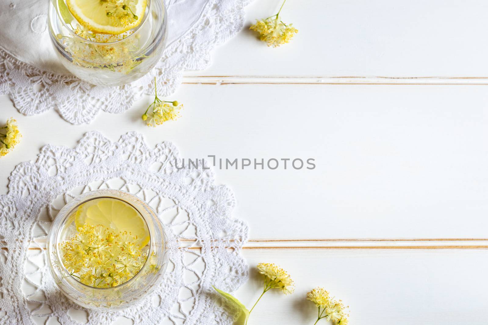 Homemade lemonade with fresh linden flowers and lemon slices, with copy space