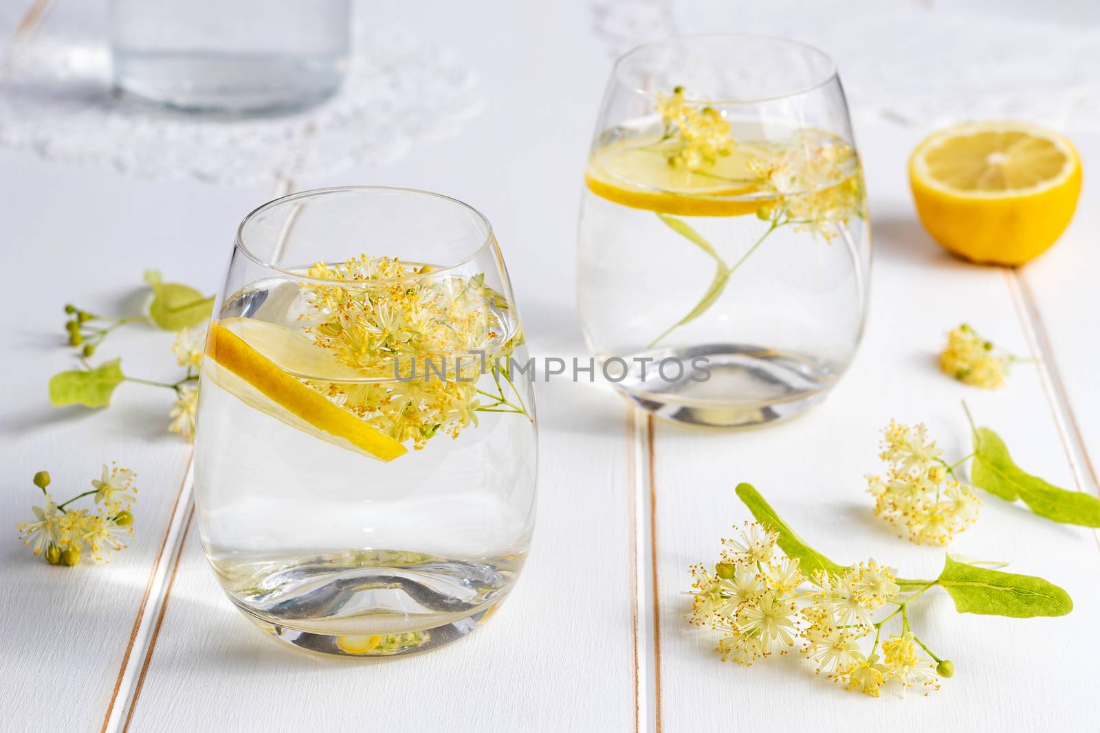 Two glasses of lemonade with fresh linden flowers and lemon