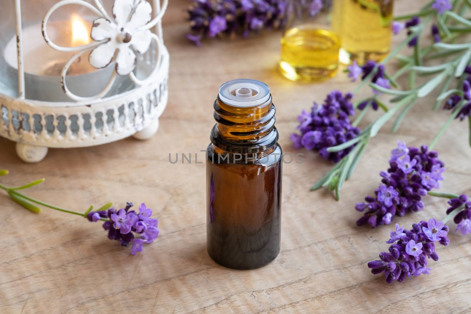 A bottle of lavender essential oil with fresh blooming lavender by madeleine_steinbach