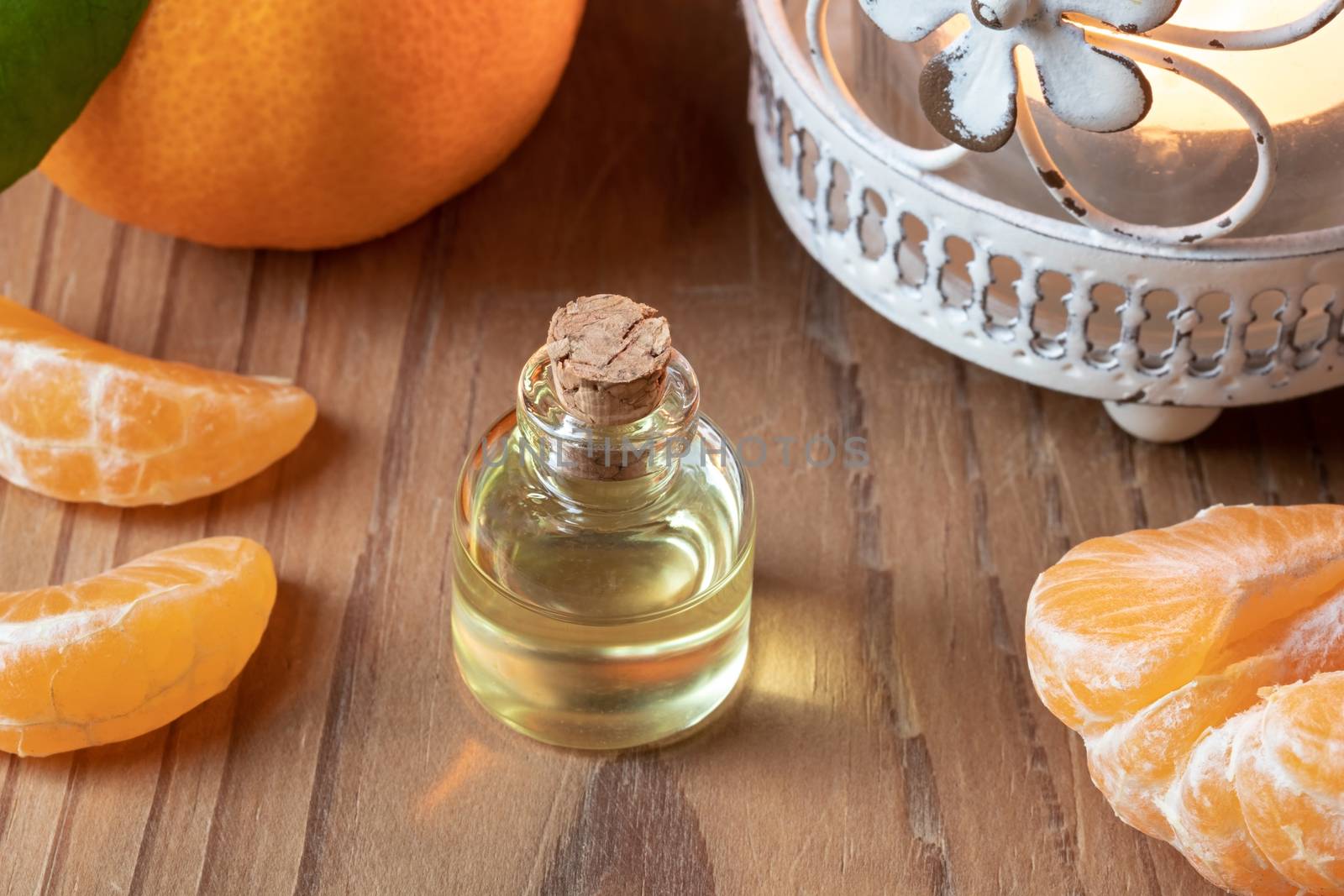 A bottle of tangerine essential oil with fresh tangerines by madeleine_steinbach