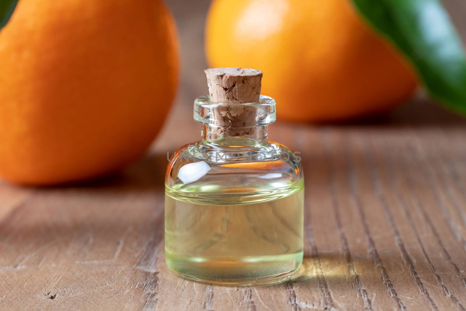 A bottle of tangerine essential oil with tangerines by madeleine_steinbach