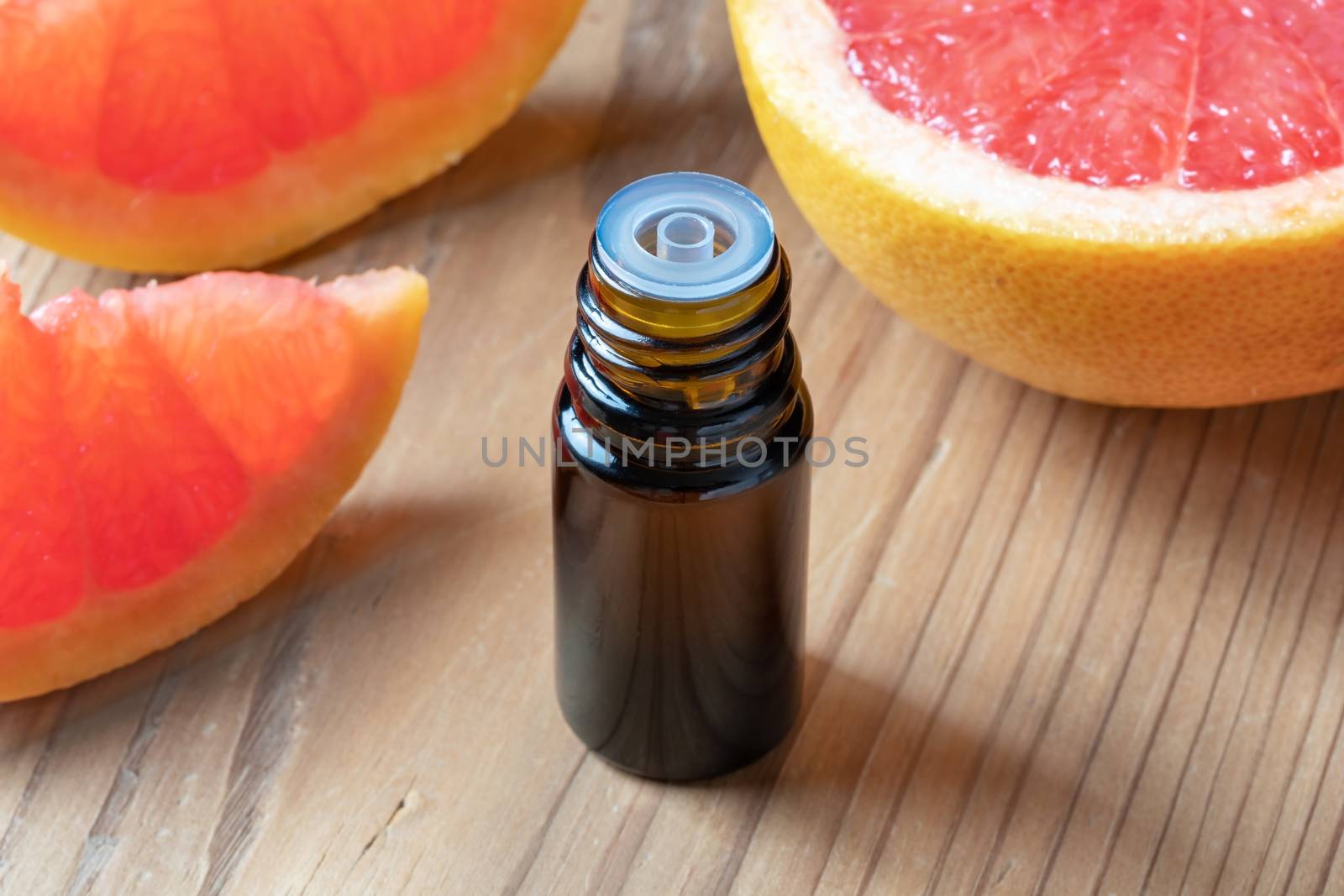 A bottle of essential oil with fresh pink grapefruit