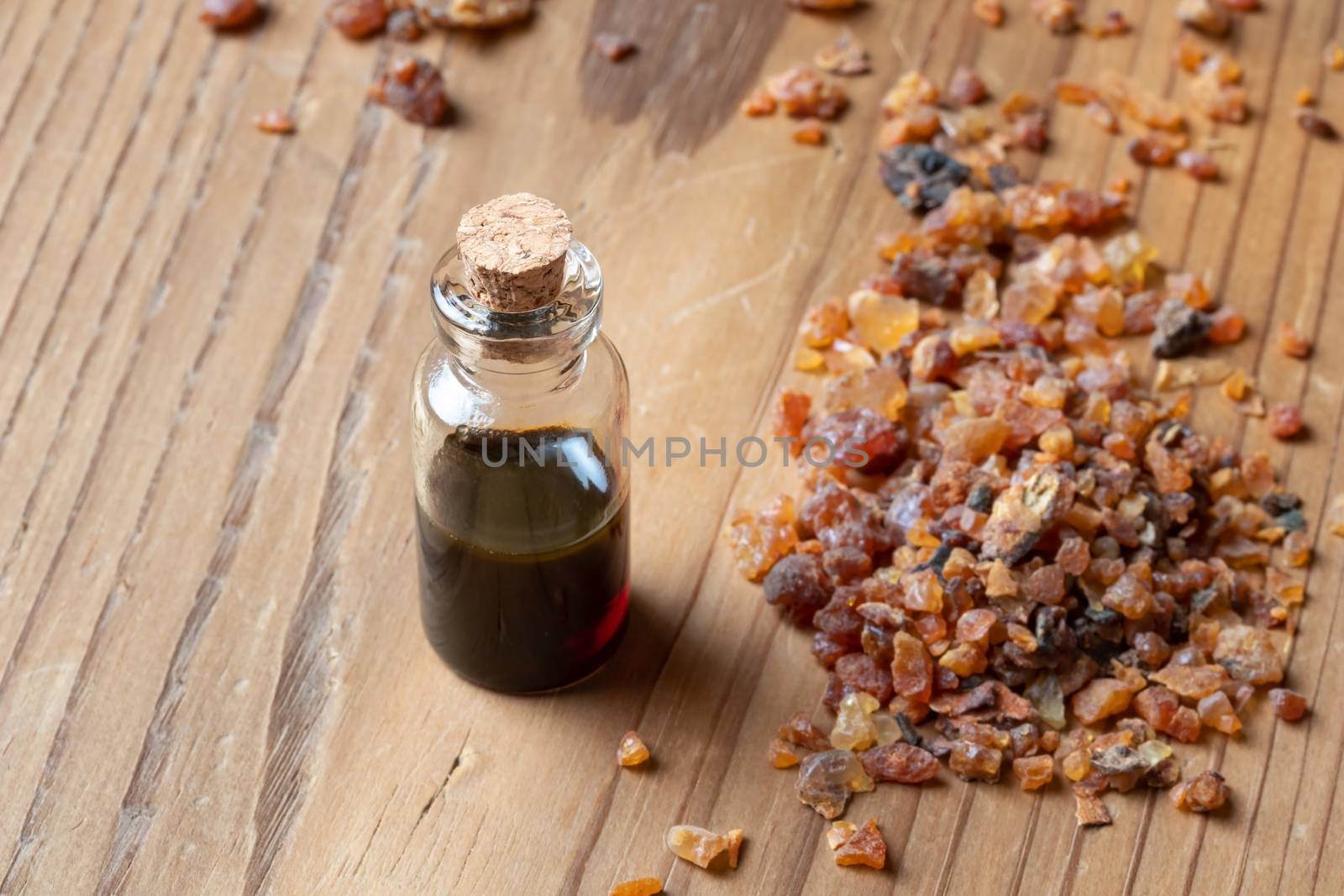 A bottle of myrrh essential oil with myrrh resin on a table by madeleine_steinbach