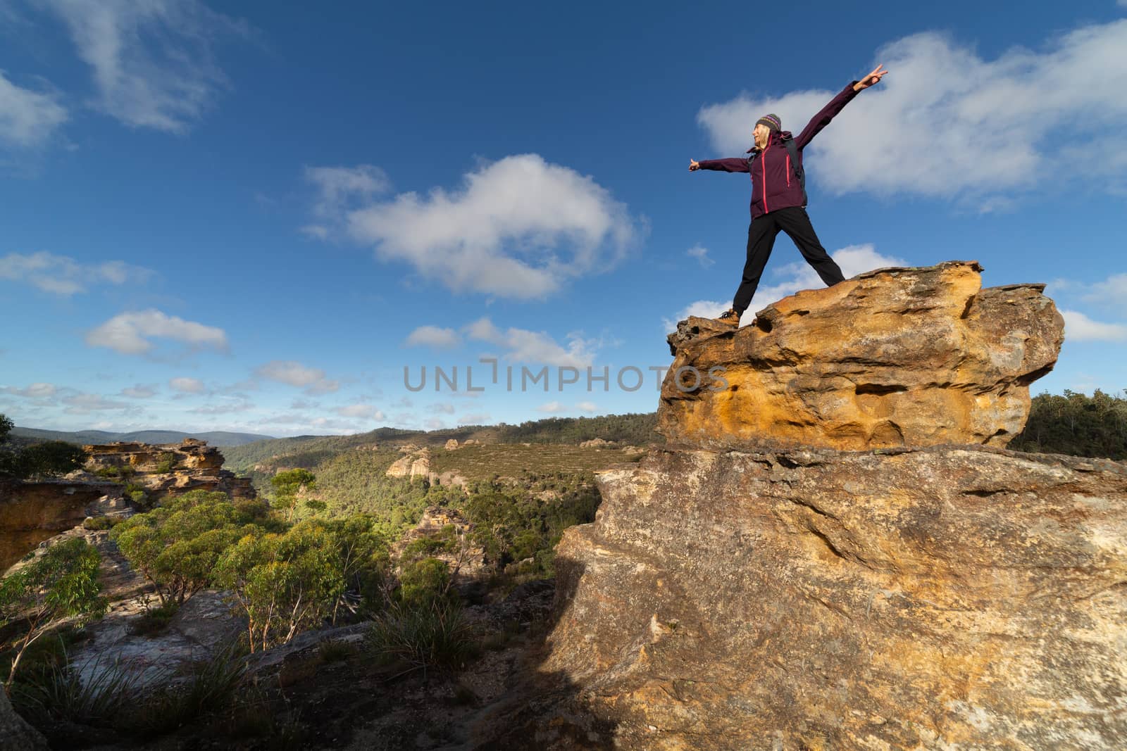 Female hiker takes in the wonderful views after climbing up pagoda, standing with victory stance, elation, success, feeling on top of the world