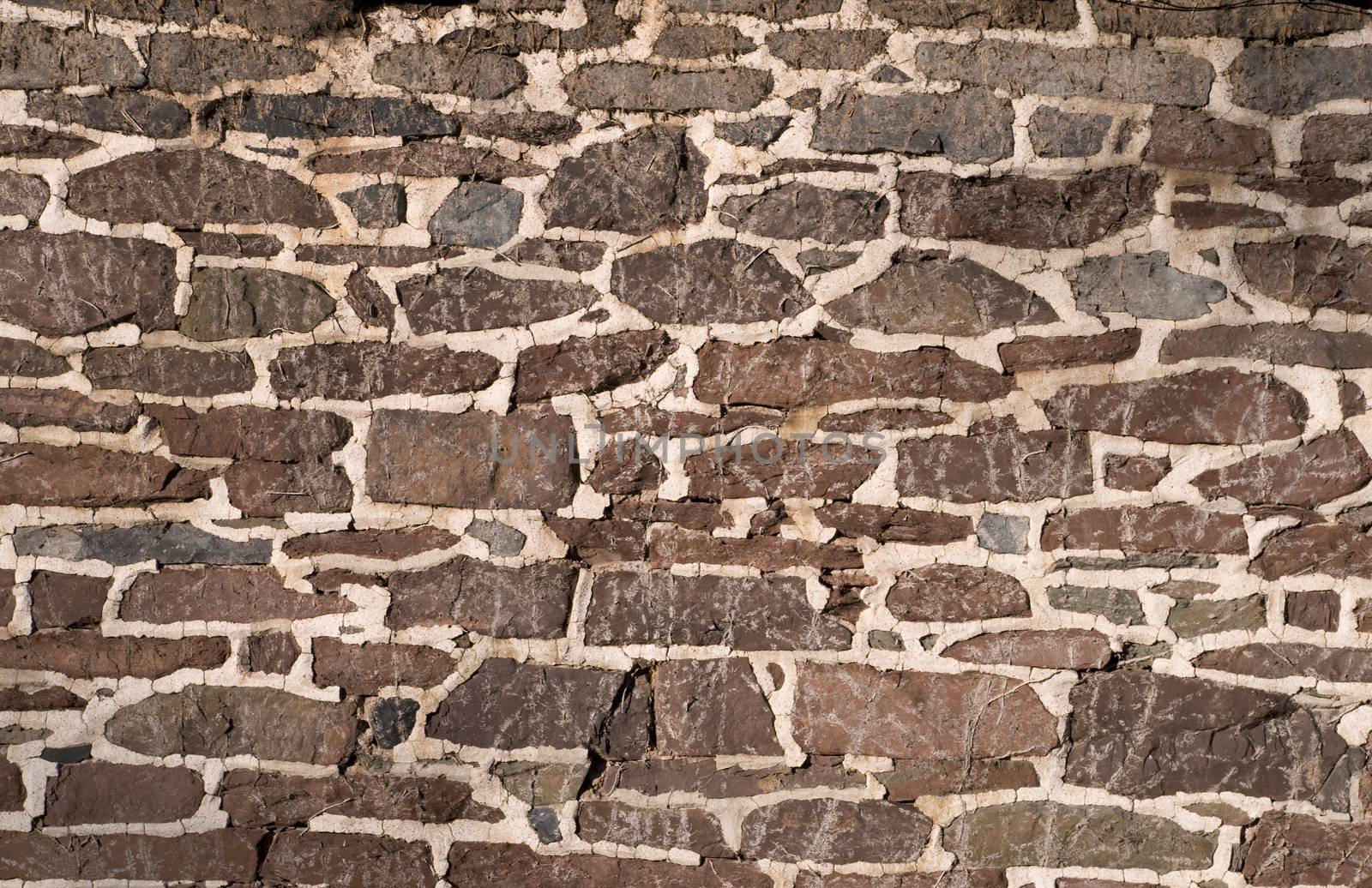 Old masonry wall using irregular red-brown stones