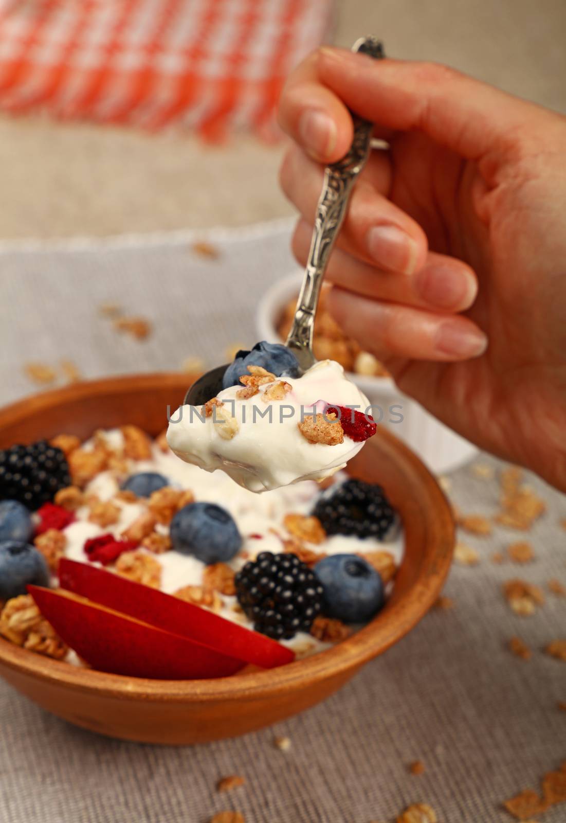 Woman eating muesli granola breakfast with yogurt by BreakingTheWalls