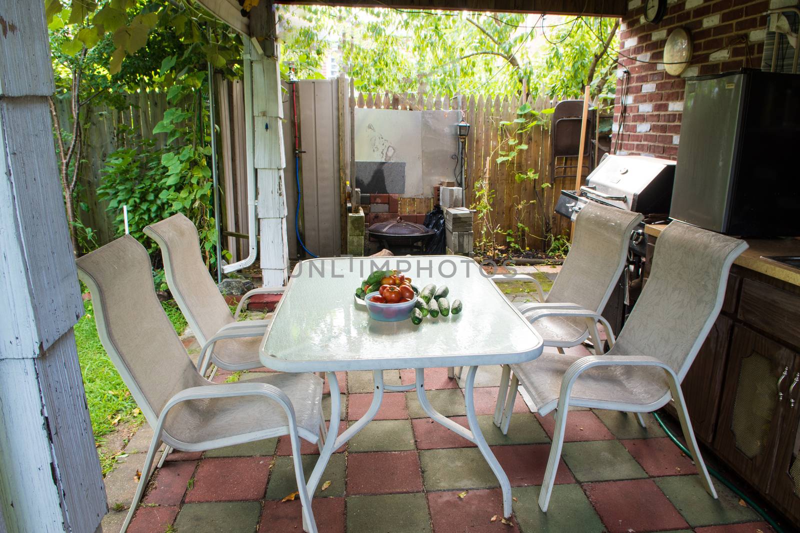 A rustic patio awaiting guests a white table with fresh vegetables and four chairs