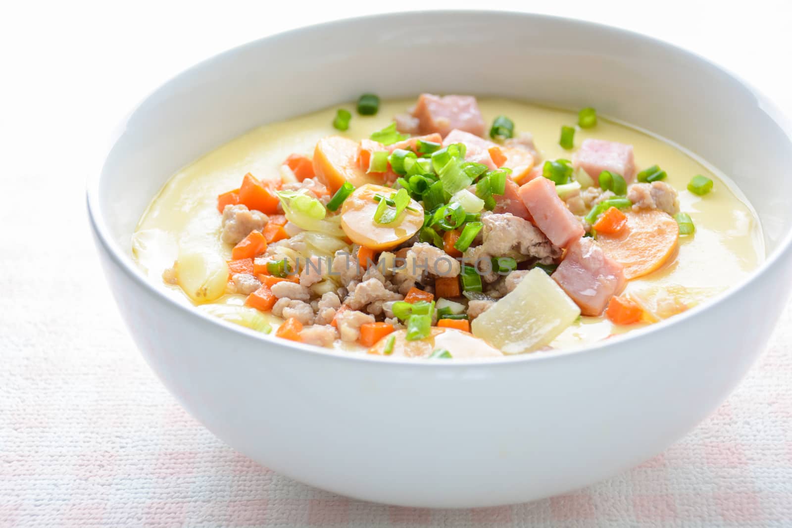 Steamed egg custard cuisine in a white bowl with minced pork, sausage and bacon.  Or Only with egg, water, salt and some sesame oil, you can make this super smooth custard at home. 
