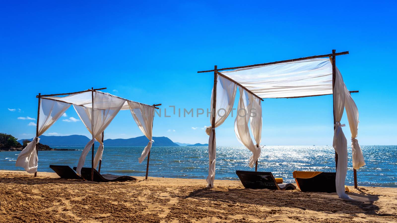 Beach canopies with sun loungers on beach.