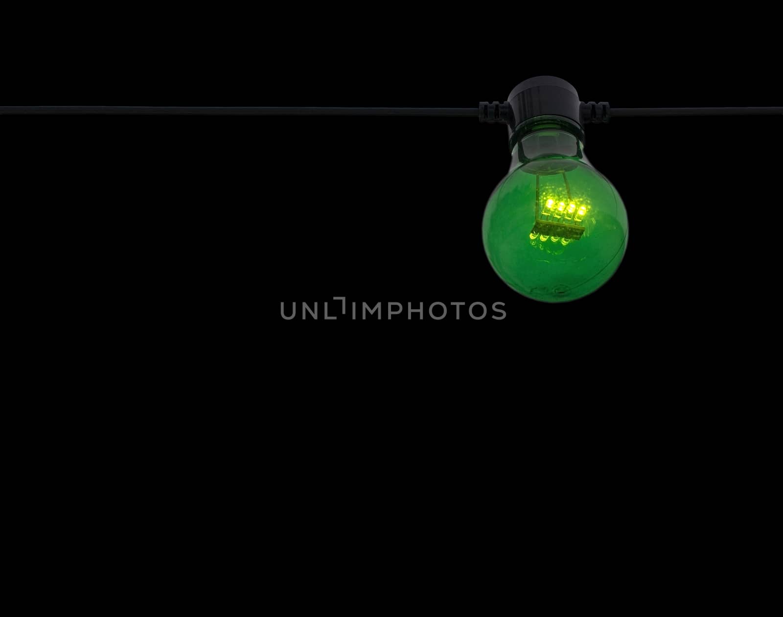 Green color lightbulb on string isolated on black