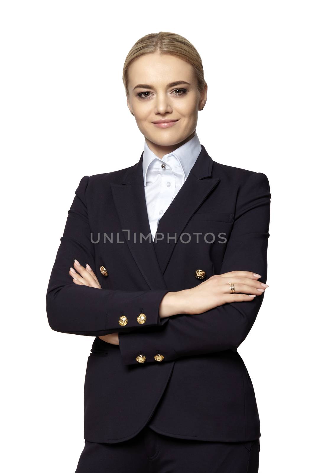 Studio portrait of young confident elegant businesswoman in a dark business suit stands with crossed hands.