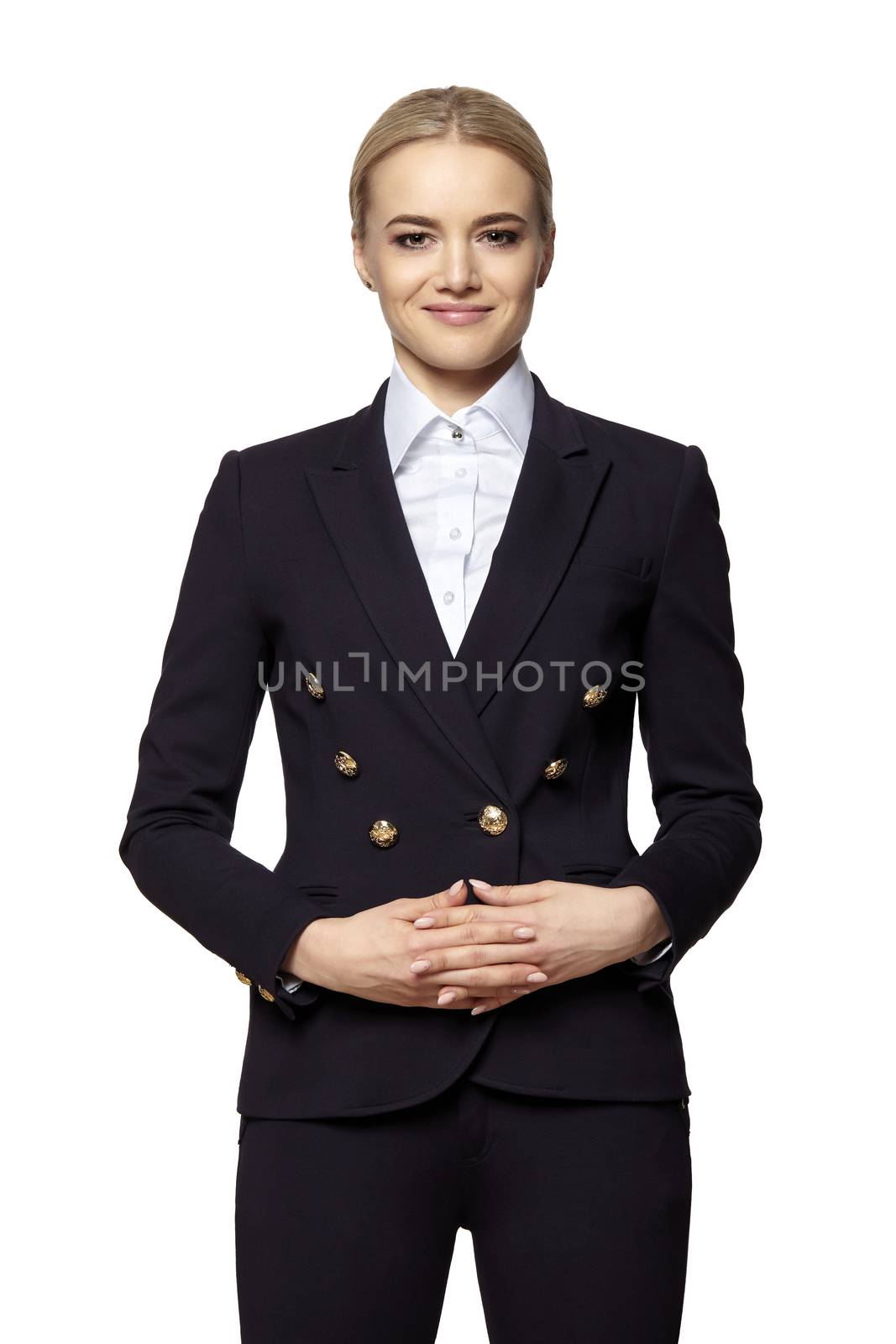 Portrait of pretty blonde in business outfit stands with folded hands.