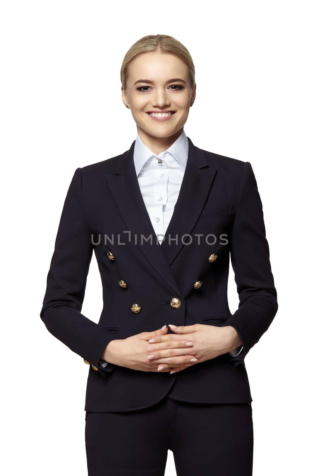 Portrait of cheerful young blonde woman in a dark business suit stands with folded hands.