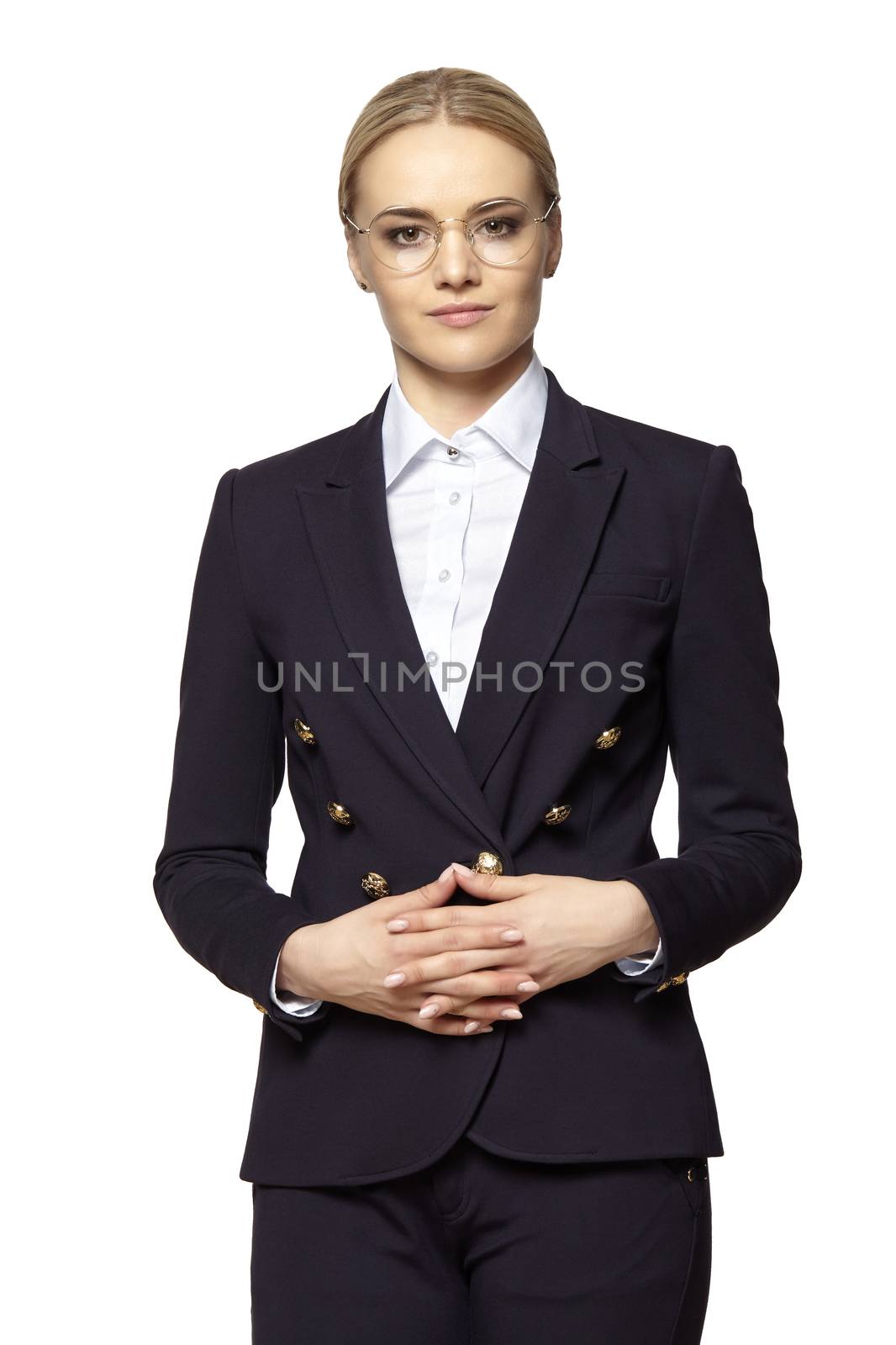 Studio portrait of pretty blonde in business outfit stands with folded hands.