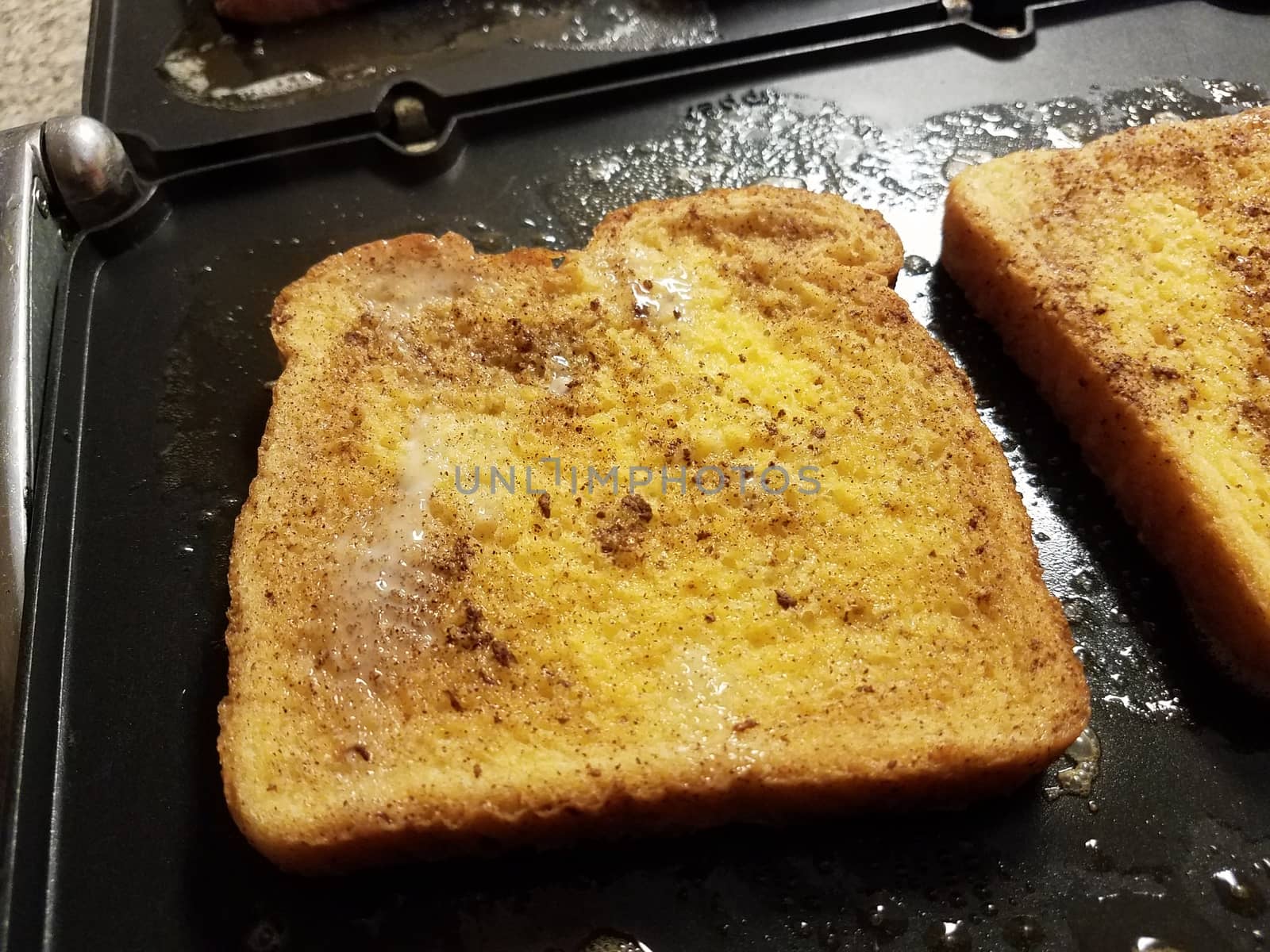 French toast bread with egg and cinnamon cooking on grill or griddle