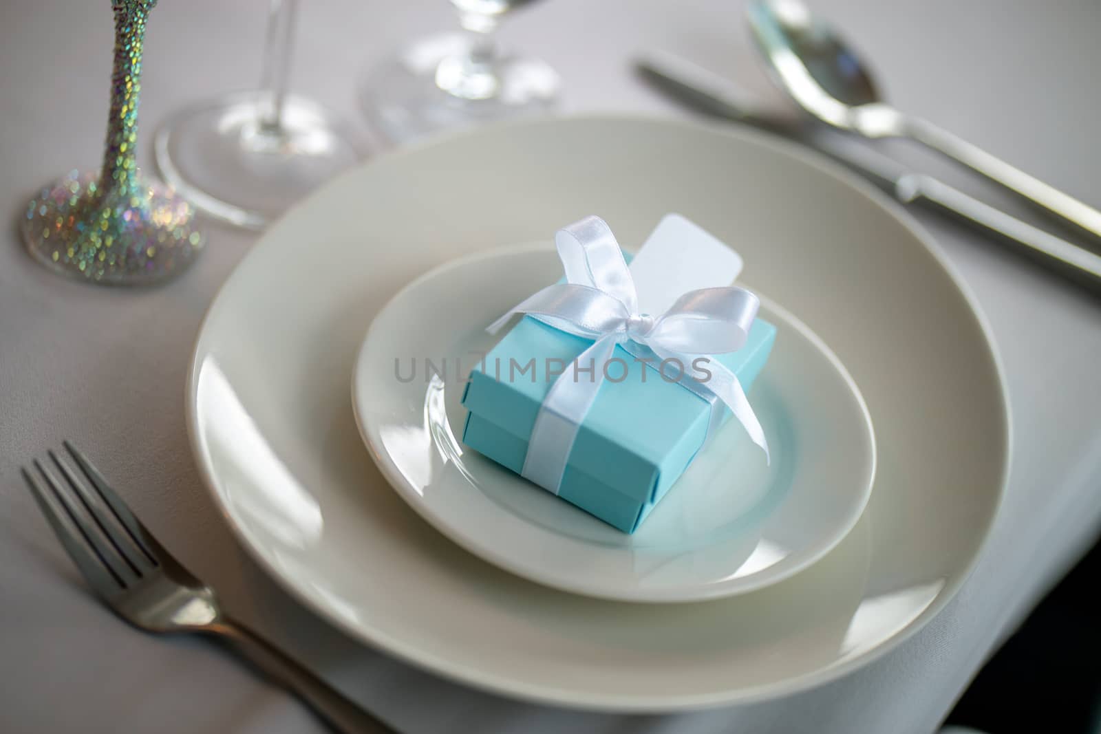 Festive table setting with handmade gift box on plate. Light blue handmade gift box in plate and fork on wedding table.
