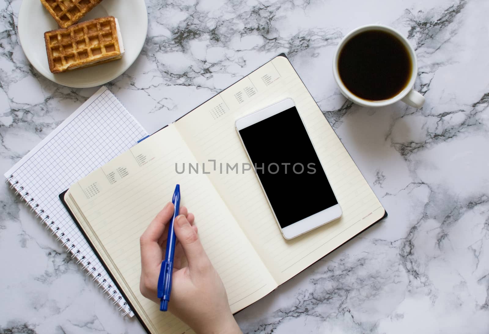 Woman are planning the day, coffee, waffles, marble background, smartphone by Izumepho