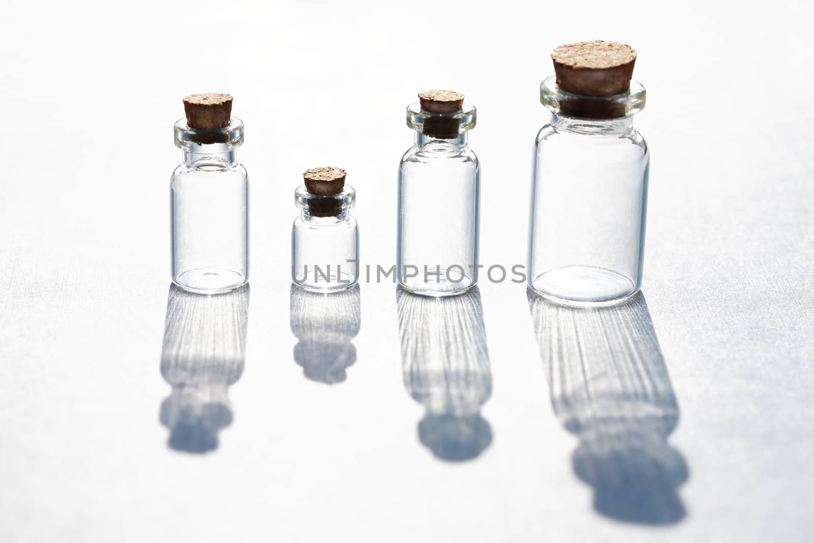 Set of small bottles with long shadow on white background