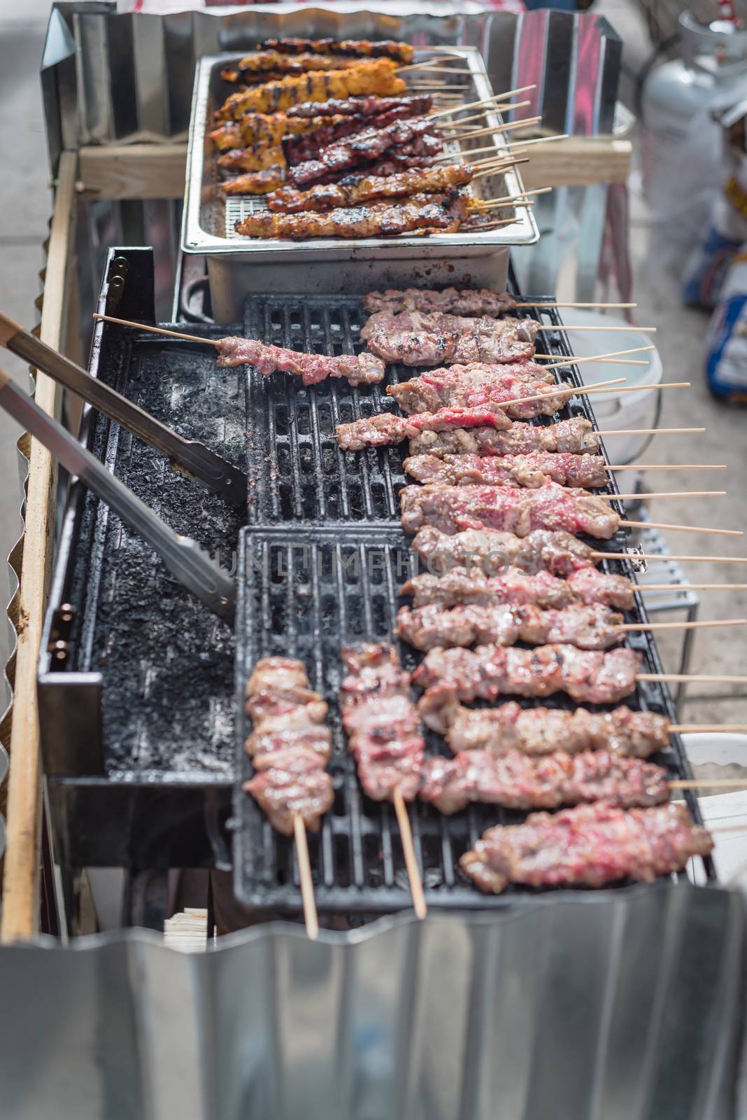 Chicken and port BBQ skewers satays on grilling racks with hot charcoal at Asian street food event in Texas, America