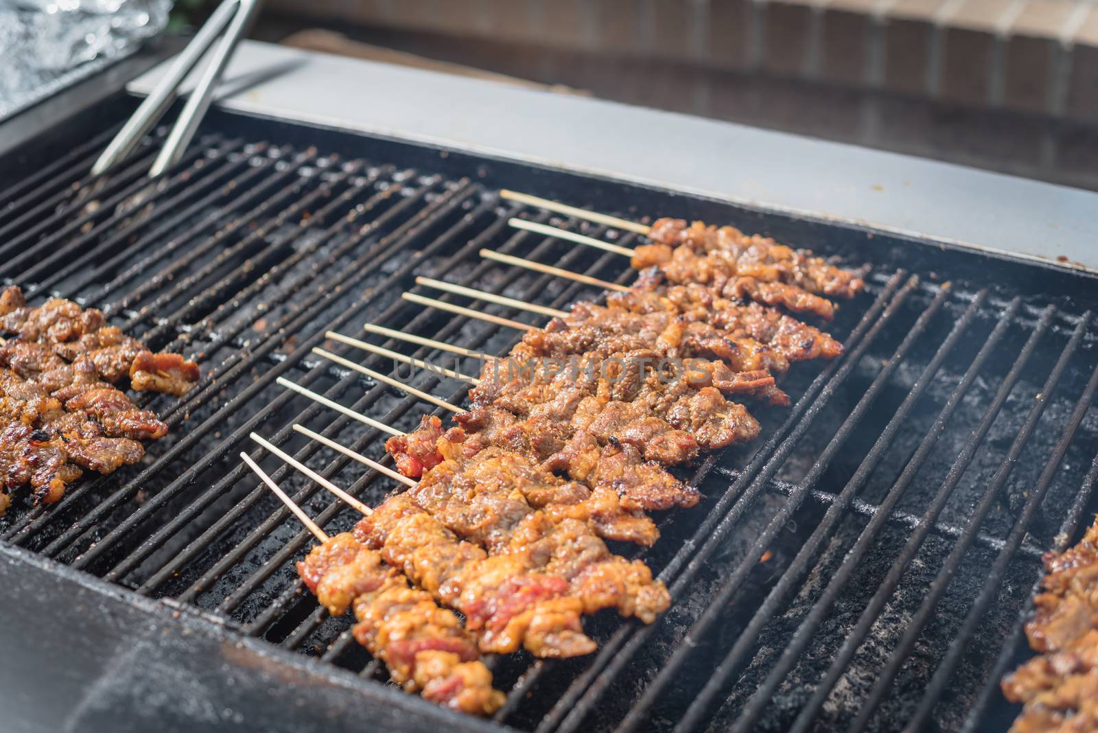 Close-up medium cooked pork BBQ skewers on grilling racks by trongnguyen
