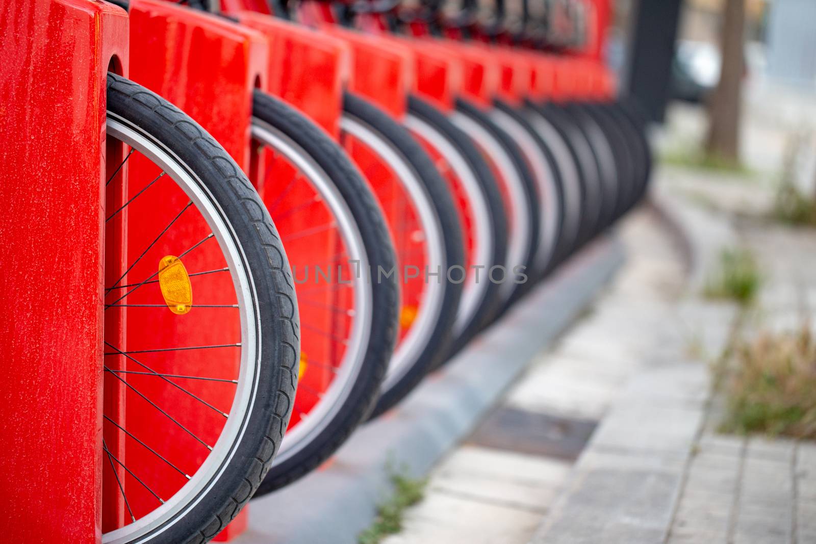 Many bicycle in a row. Red bicycles stand on a parking for rent. Eco friendly transportation concept.