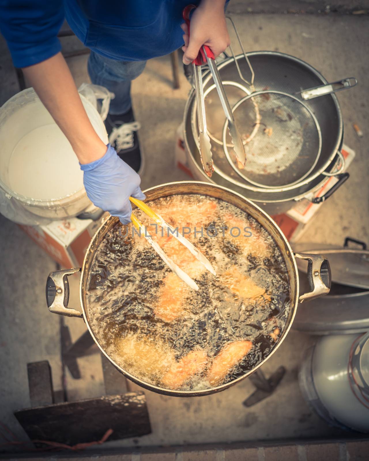 Top view hands in gloves with stainless steel tong turning deep fried rice flour cakes in hot and flaming oil pot.  Popular Vietnamese cuisine and a Chinese-influenced pastry