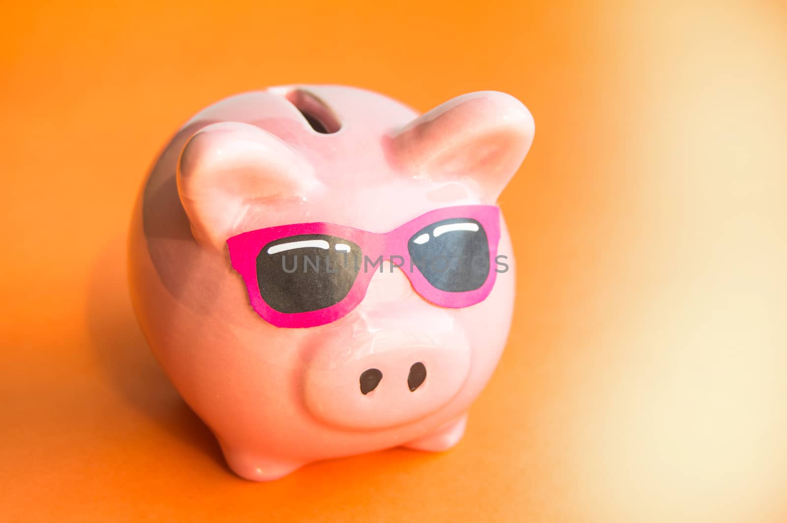 Funny piggy Bank in sunglasses on orange background, sunlight, copy space, money saving concept for summer vacation by claire_lucia