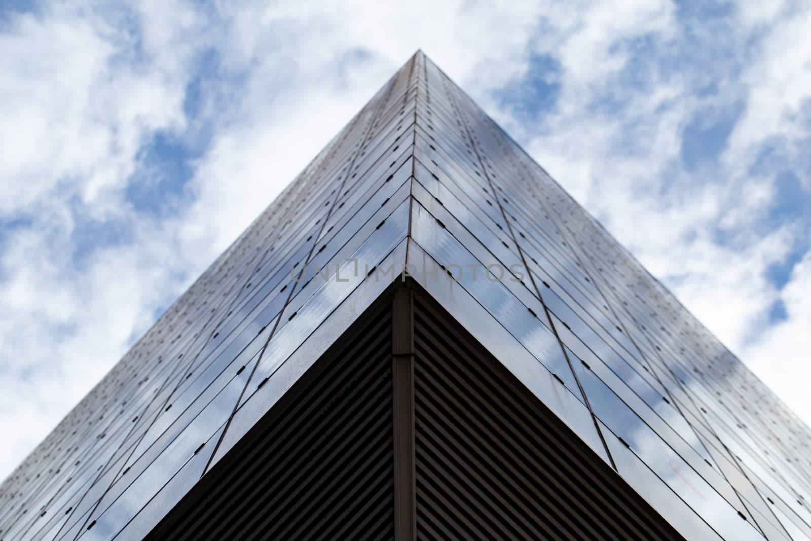 Glass architecture. Photo from the bottom of the modern facade of an office building. Sample of a dynamic business cityscape. Abstract high-tech composition with glazing.