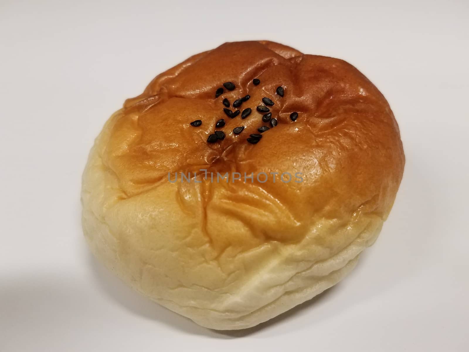 bread or bun with black seeds on white surface by stockphotofan1