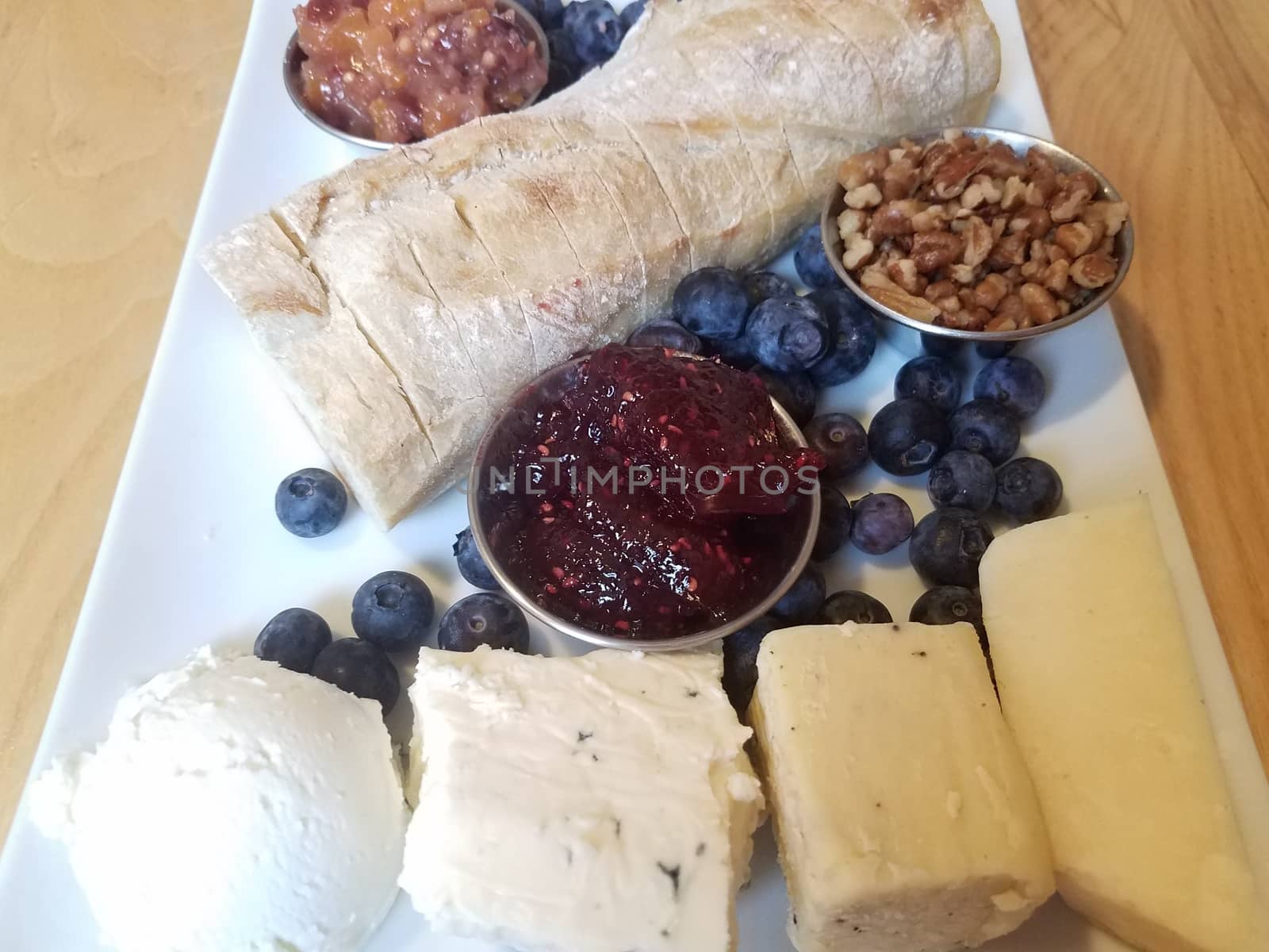 cheese pecans and bread and blueberries with jam on white plate