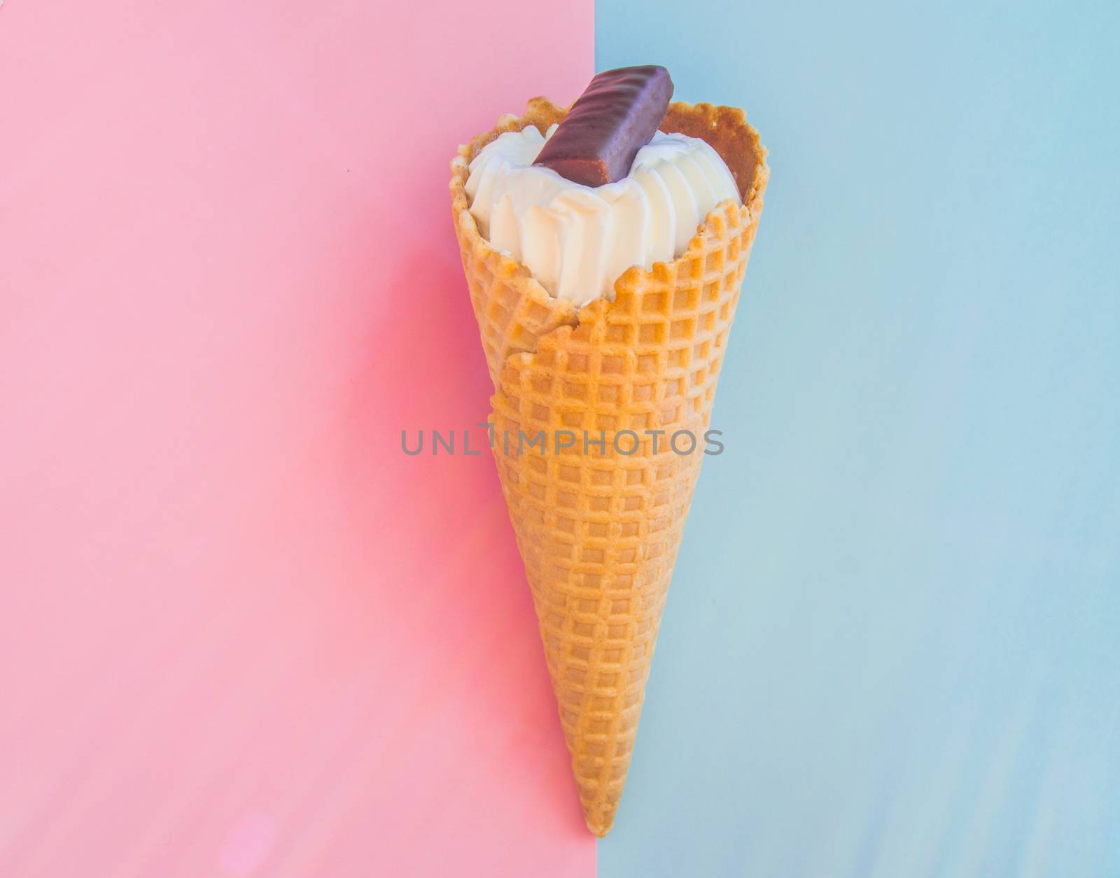 Vanilla ice cream cone with chocolate on a background of pastel colors pink and blue.