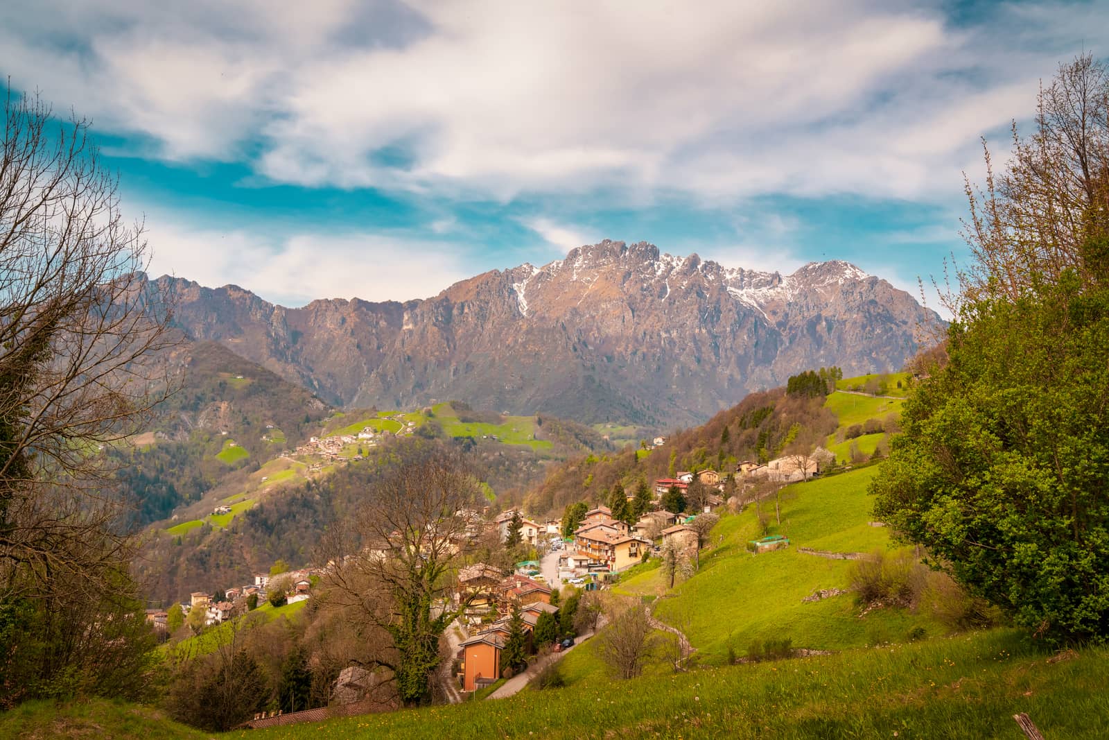 Landscape of green hills in Orobie mountains,background view of mountain peaks in spring time with snow, Seriana valley near Bergamo,Lombardy,italy