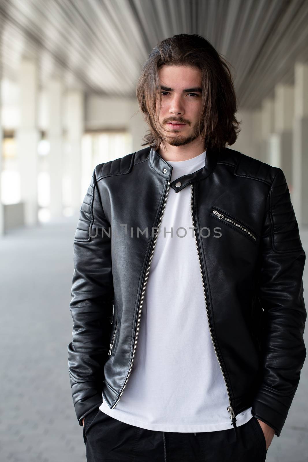 Half length portrait of handsome bearded man dressed in fashionable clothes standing on street against while wall background with area for advertising content. Handsome hipster guy posing on copy space