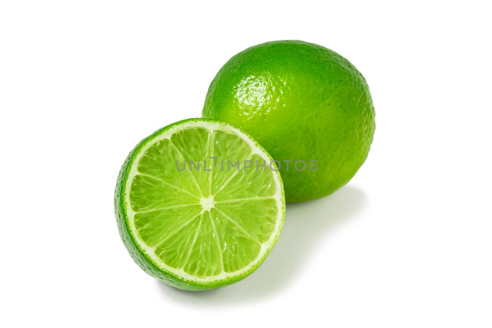 Fresh ripe limes, one whole and one half isolated on white background with shadow - image.