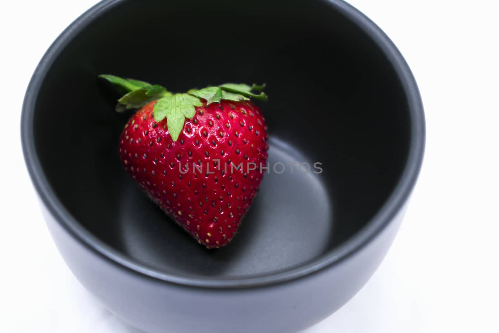 A Lone Strawberry in a Black Bowl
