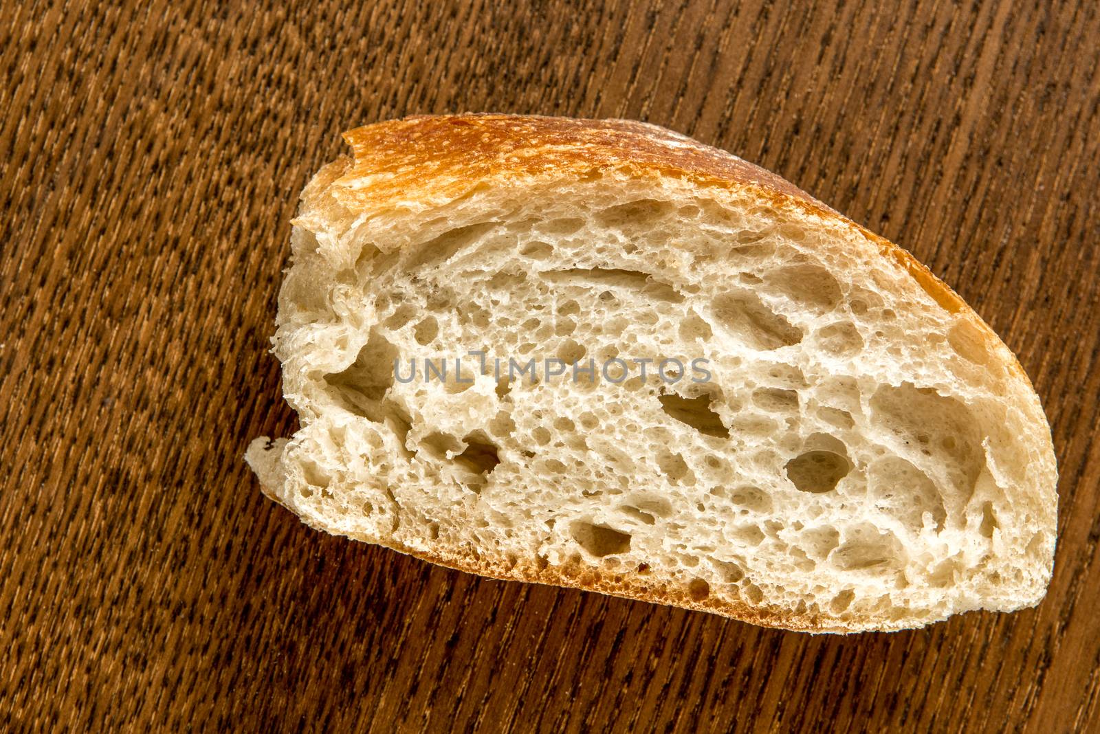 A piece of white baguette with an interesting texture is on the table