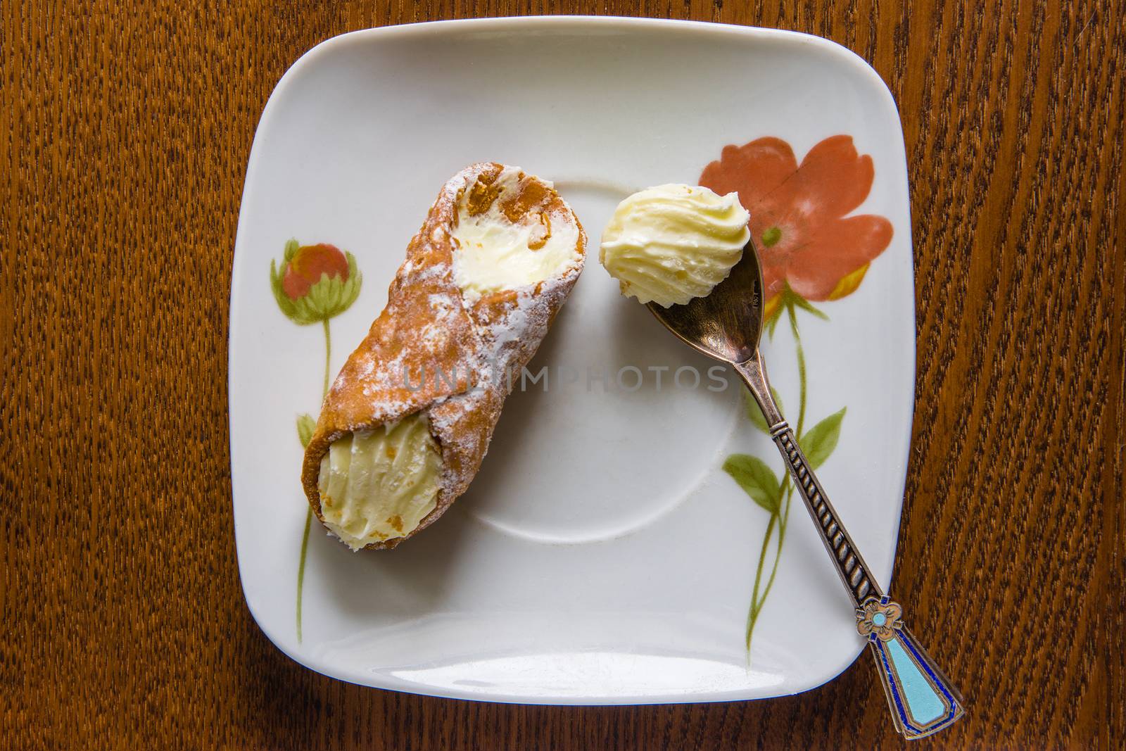 Italian canola cake and cream spoon are on a ceramic plate
