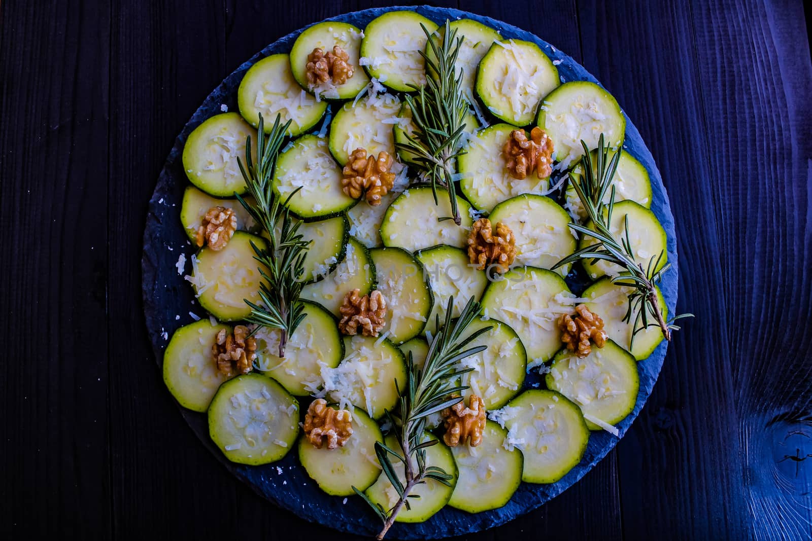 Carpaccio of zucchini with nuts and cheese on dark wooden background