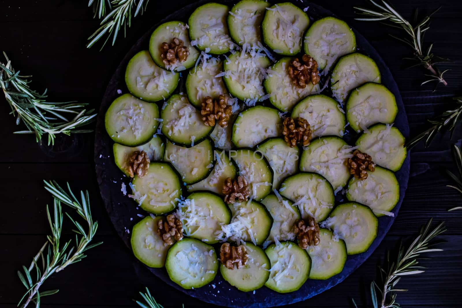 Carpaccio of zucchini with nuts and cheese on dark wooden background