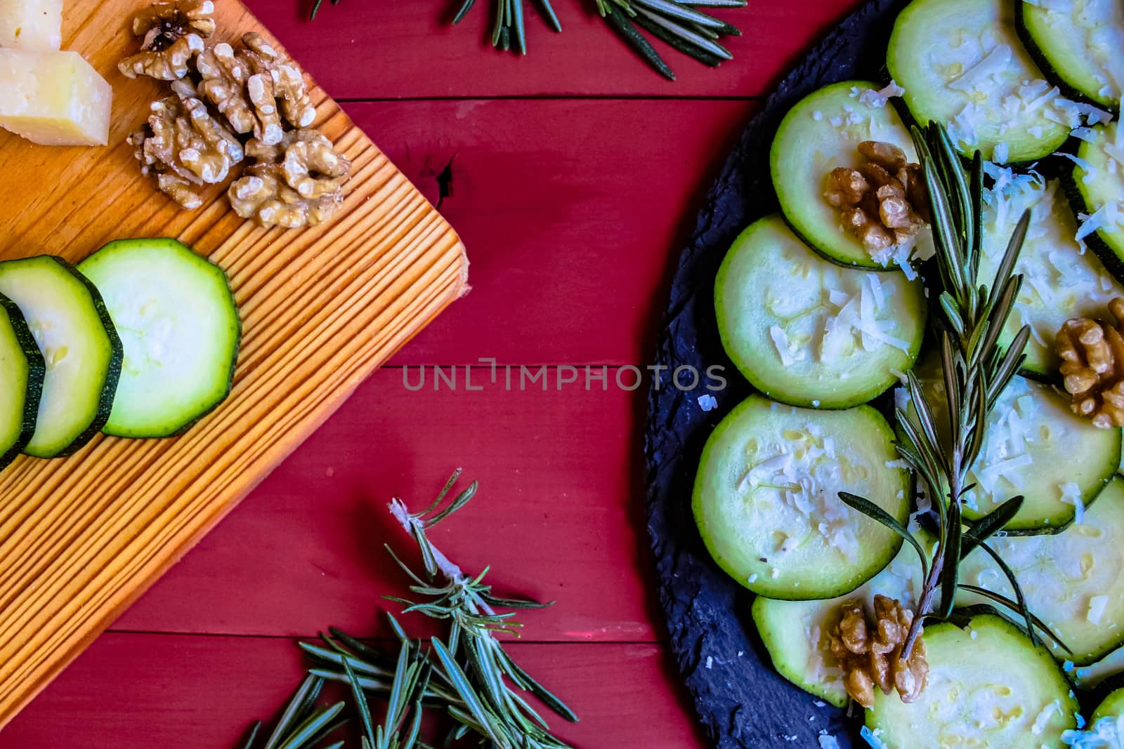 Carpaccio of zucchini with nuts and cheese on red wooden background