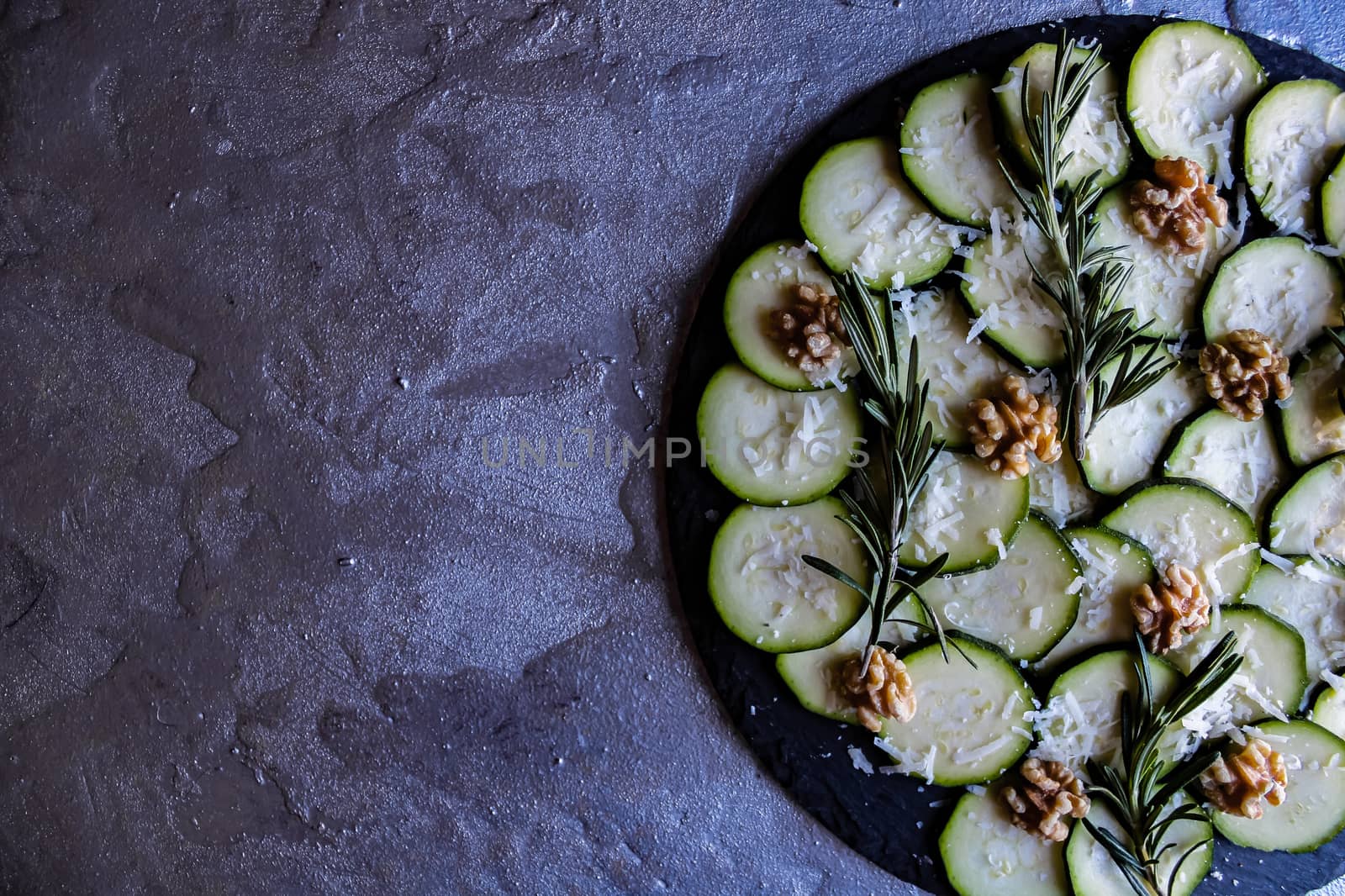 Carpaccio of zucchini with nuts and cheese on gray background