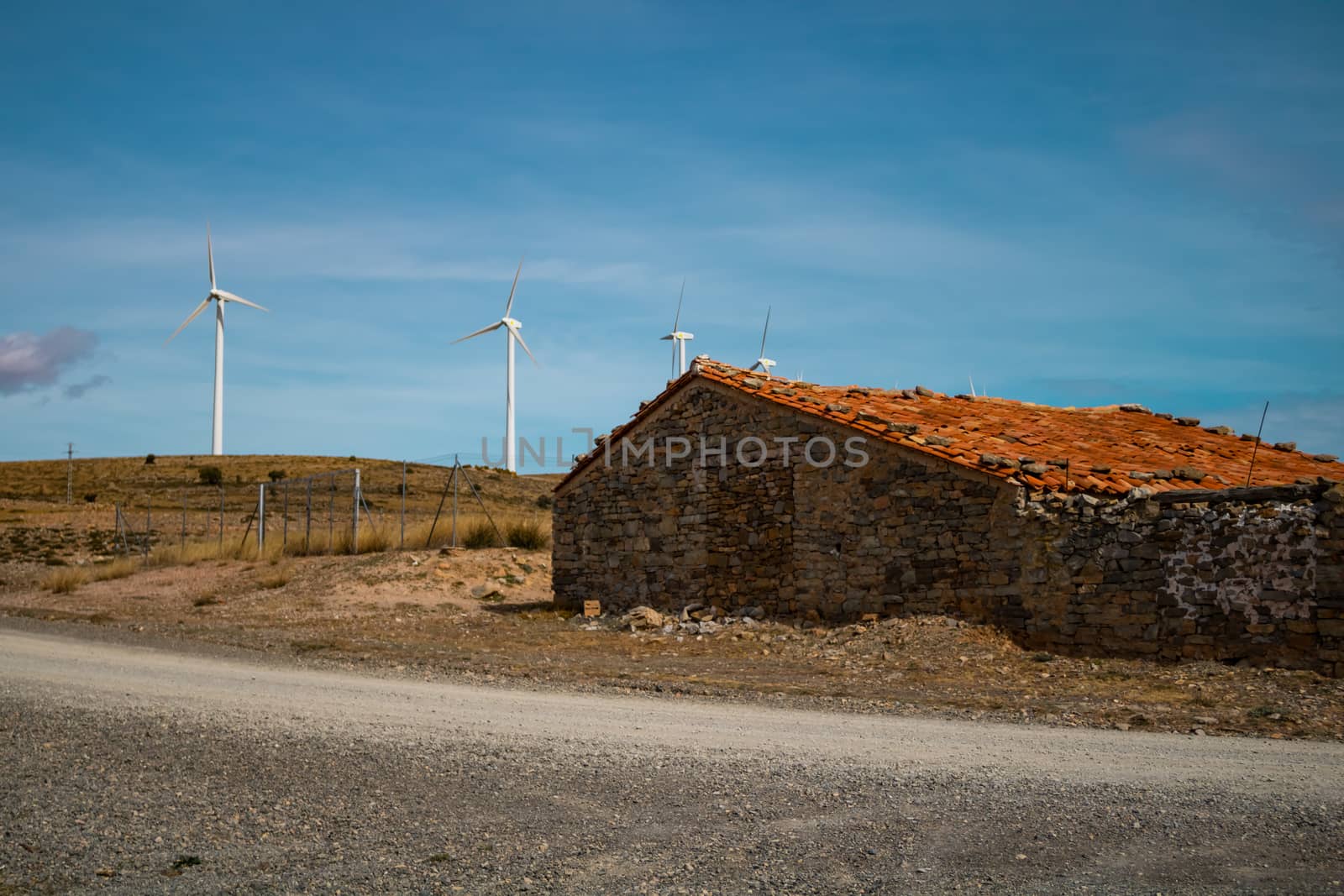 Old abandoned stone house with windmills in the background
