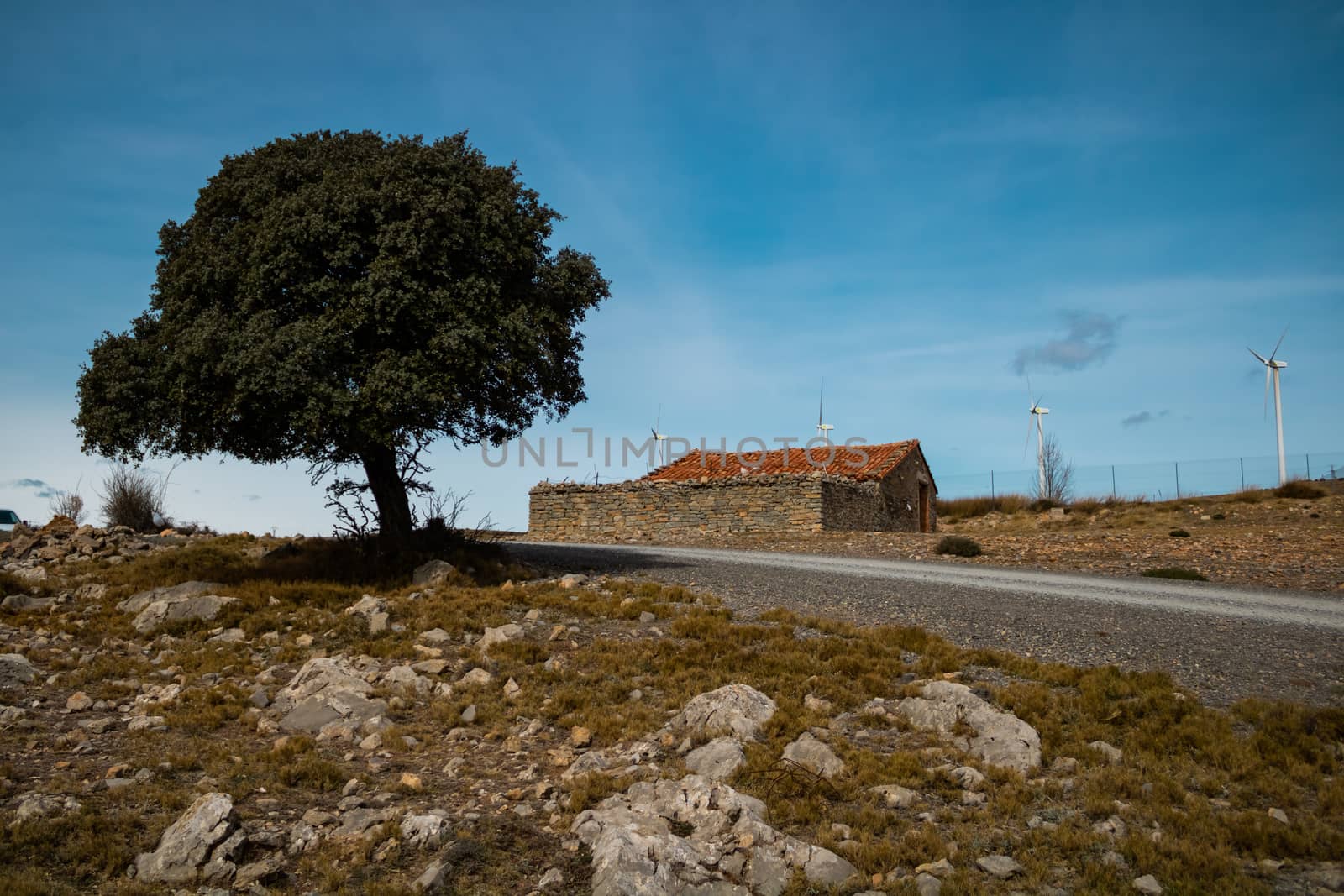 Old abandoned stone house with windmills in the background
