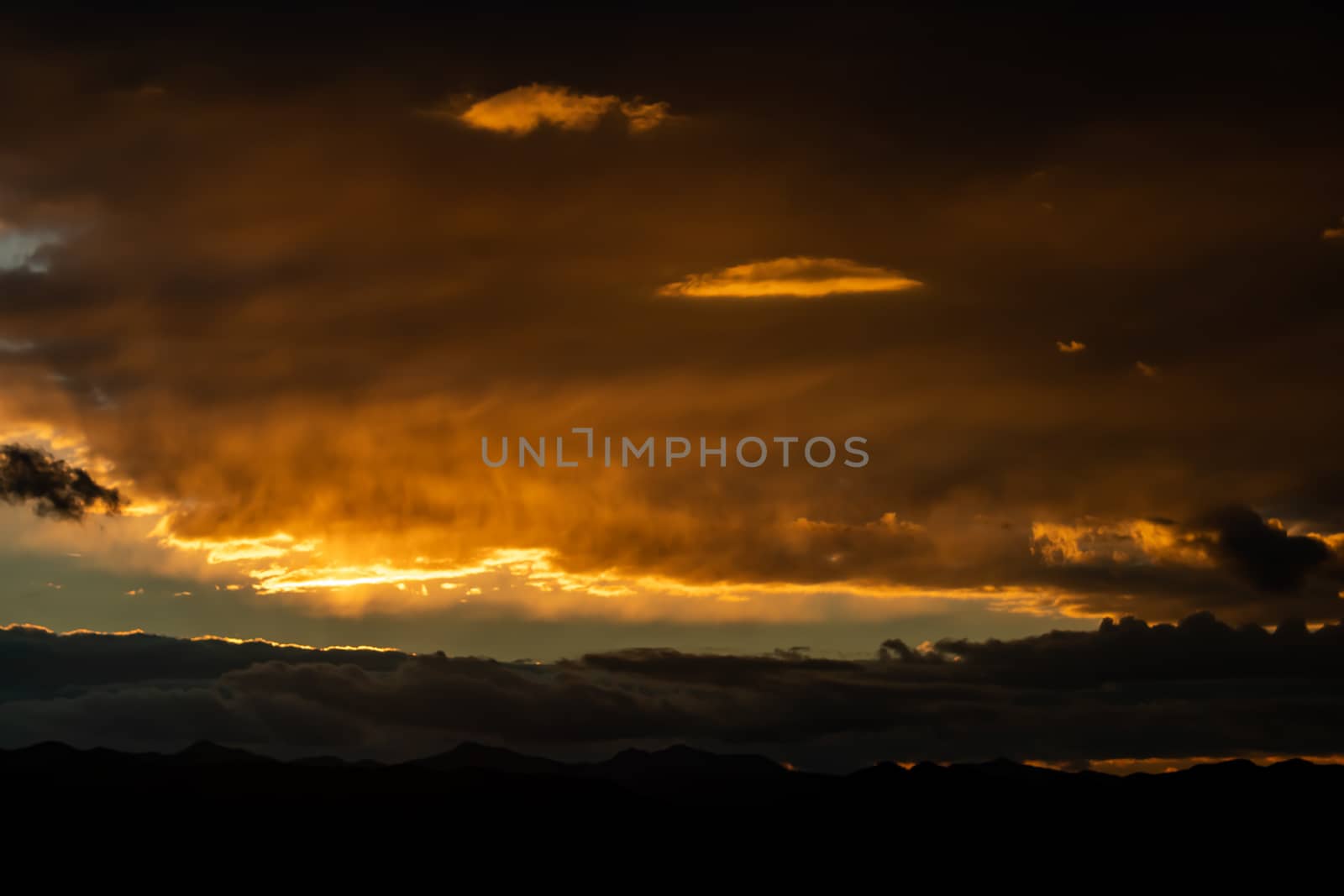 Sunset over mountains with storms clouds